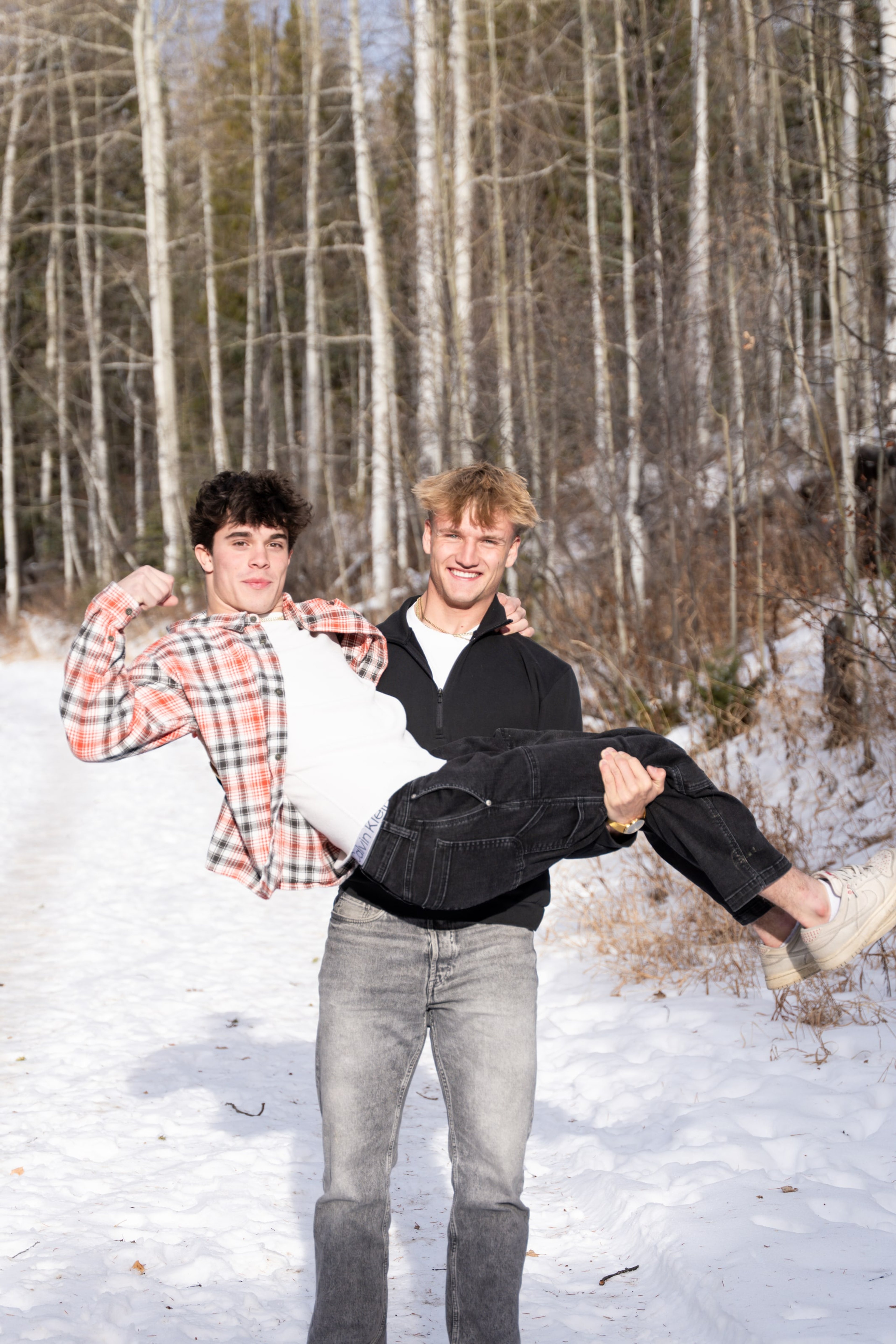 Ryder carrying Jakob through the snow, both laughing