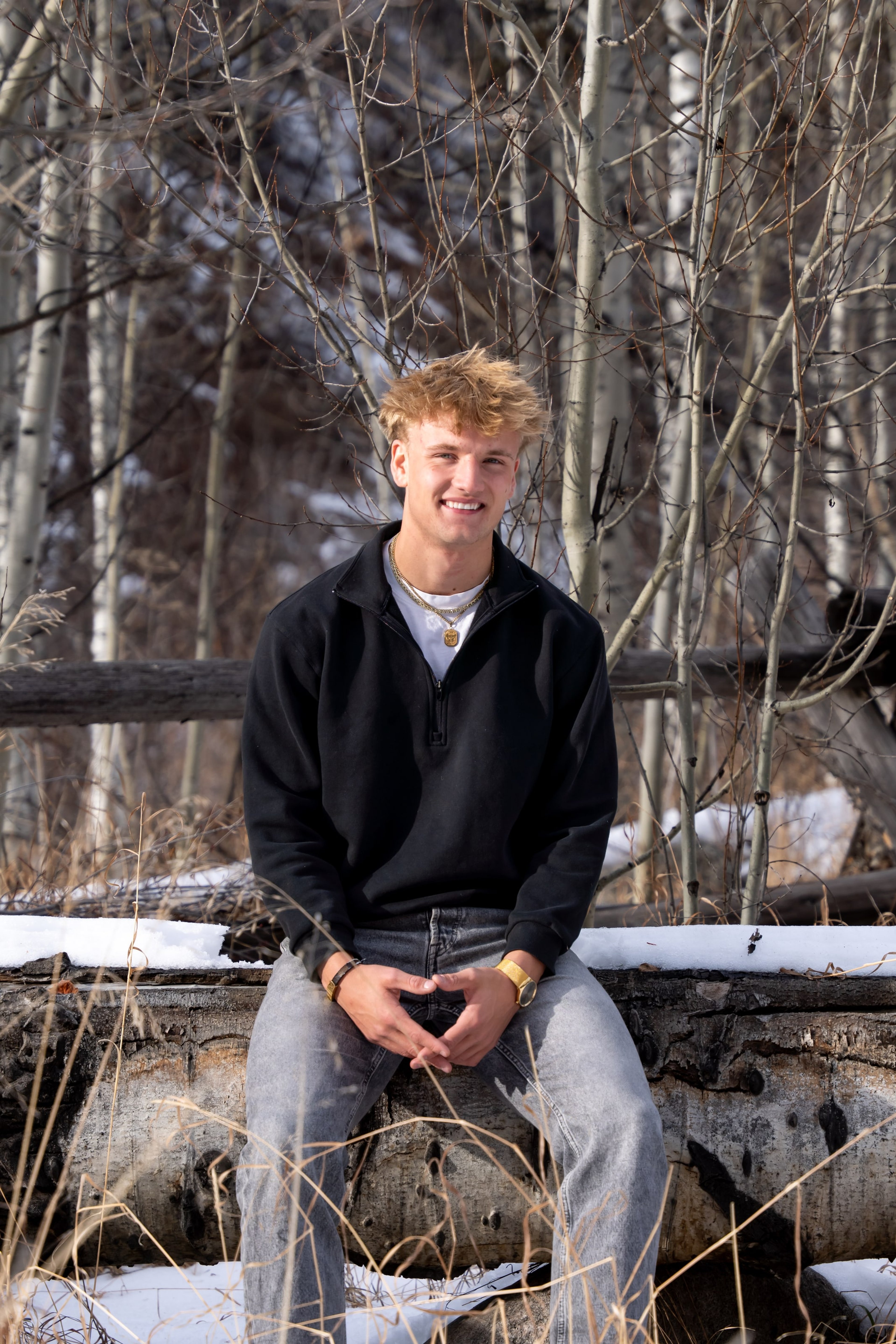 Jakob seated on a stone wall in the winter grove
