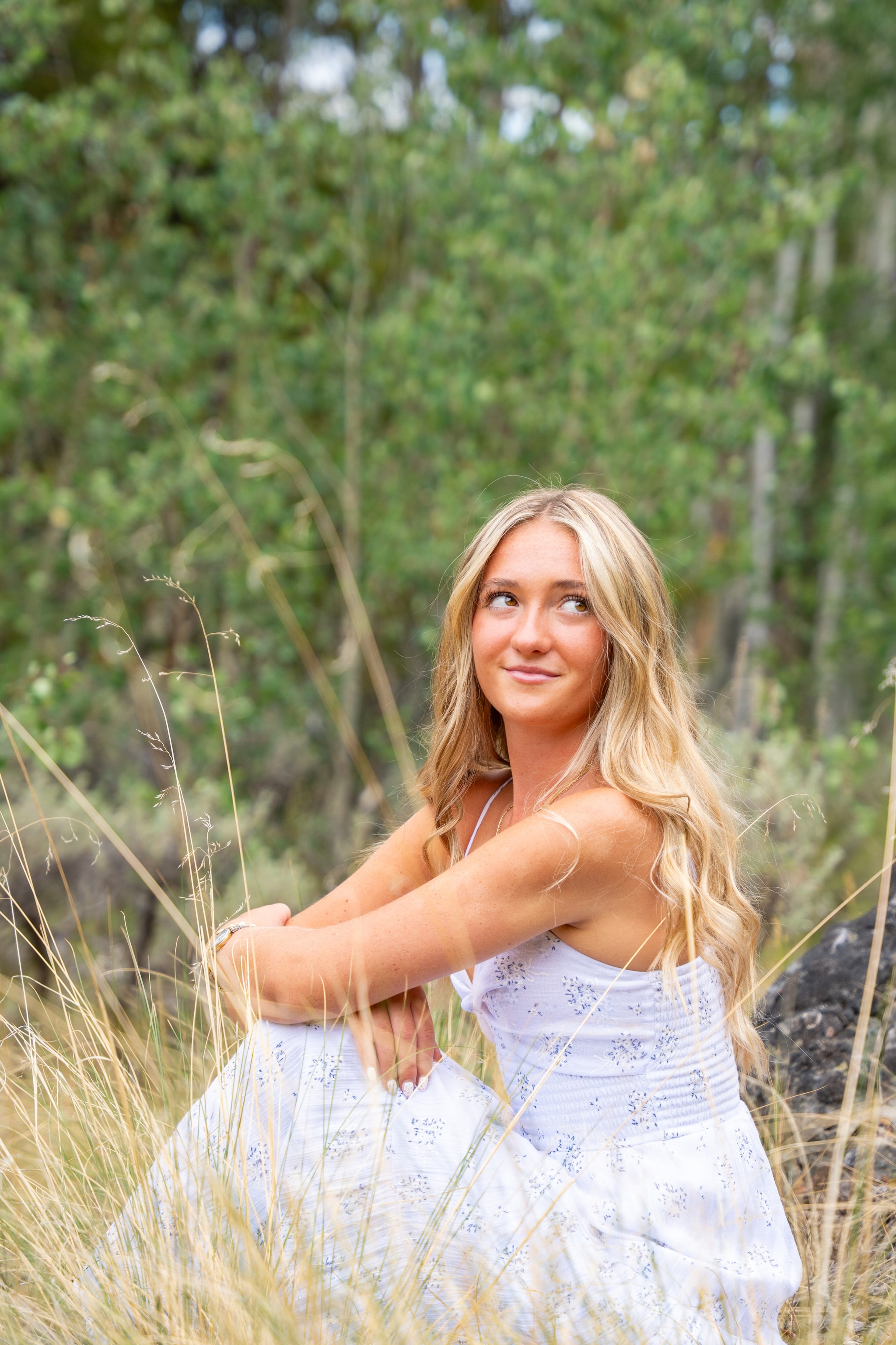 Caleigh sitting in meadow grass in a pale blue dress