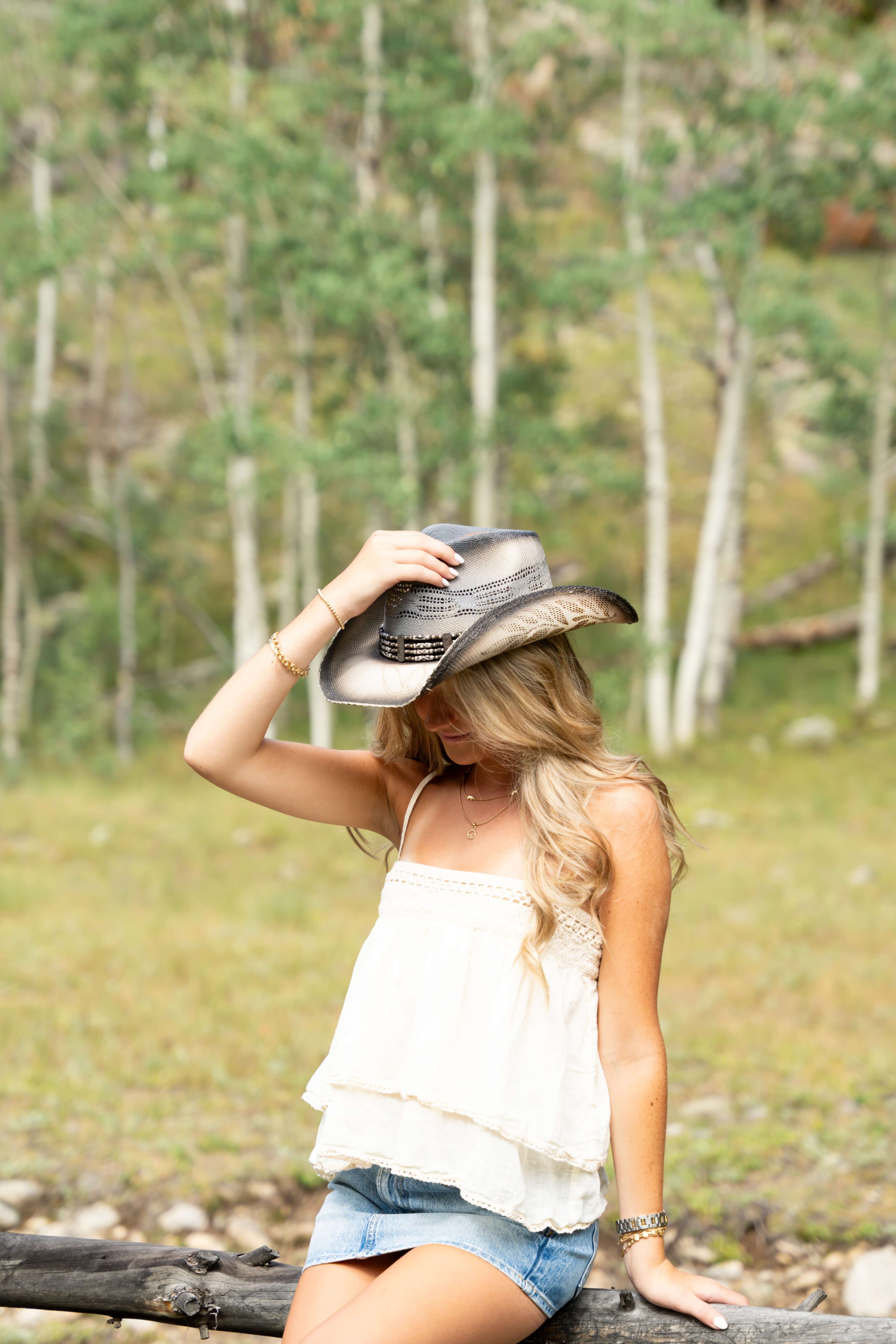Caleigh tipping her cowboy hat beside a grove of aspens
