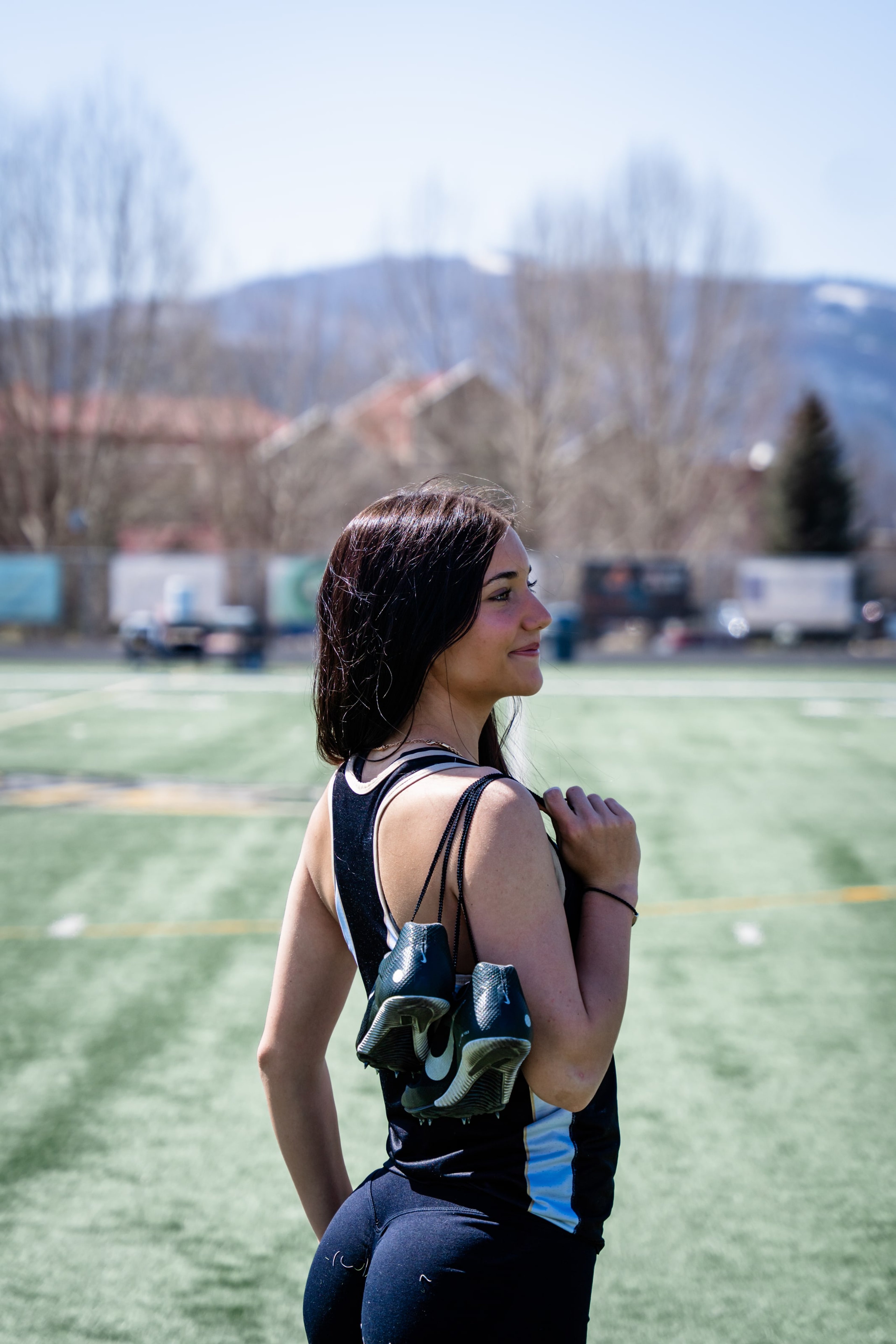 Lucy glancing back with spikes slung over her shoulder on the green