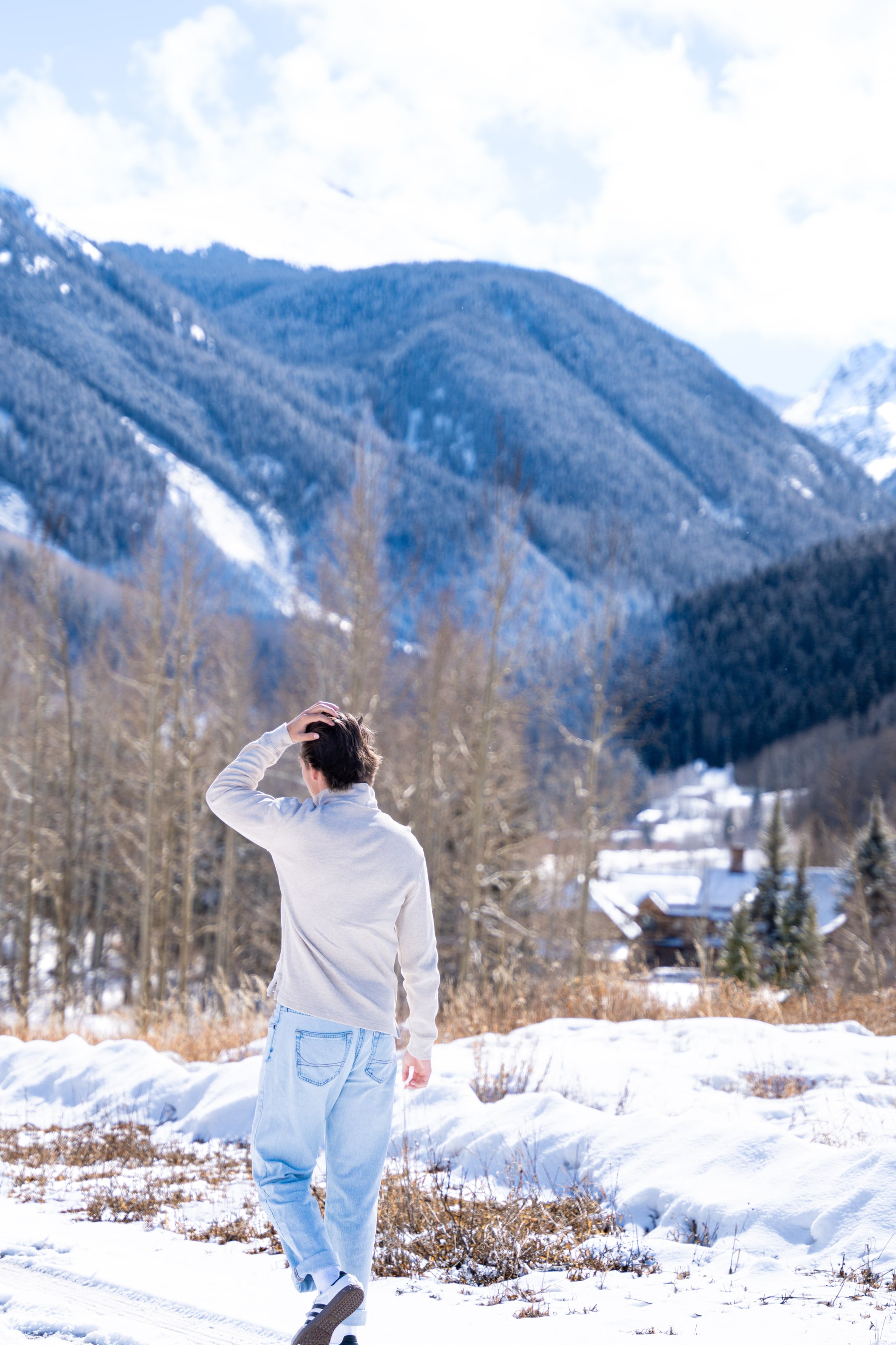 Caeden looking out over the snow-covered valley, hand raised against the light