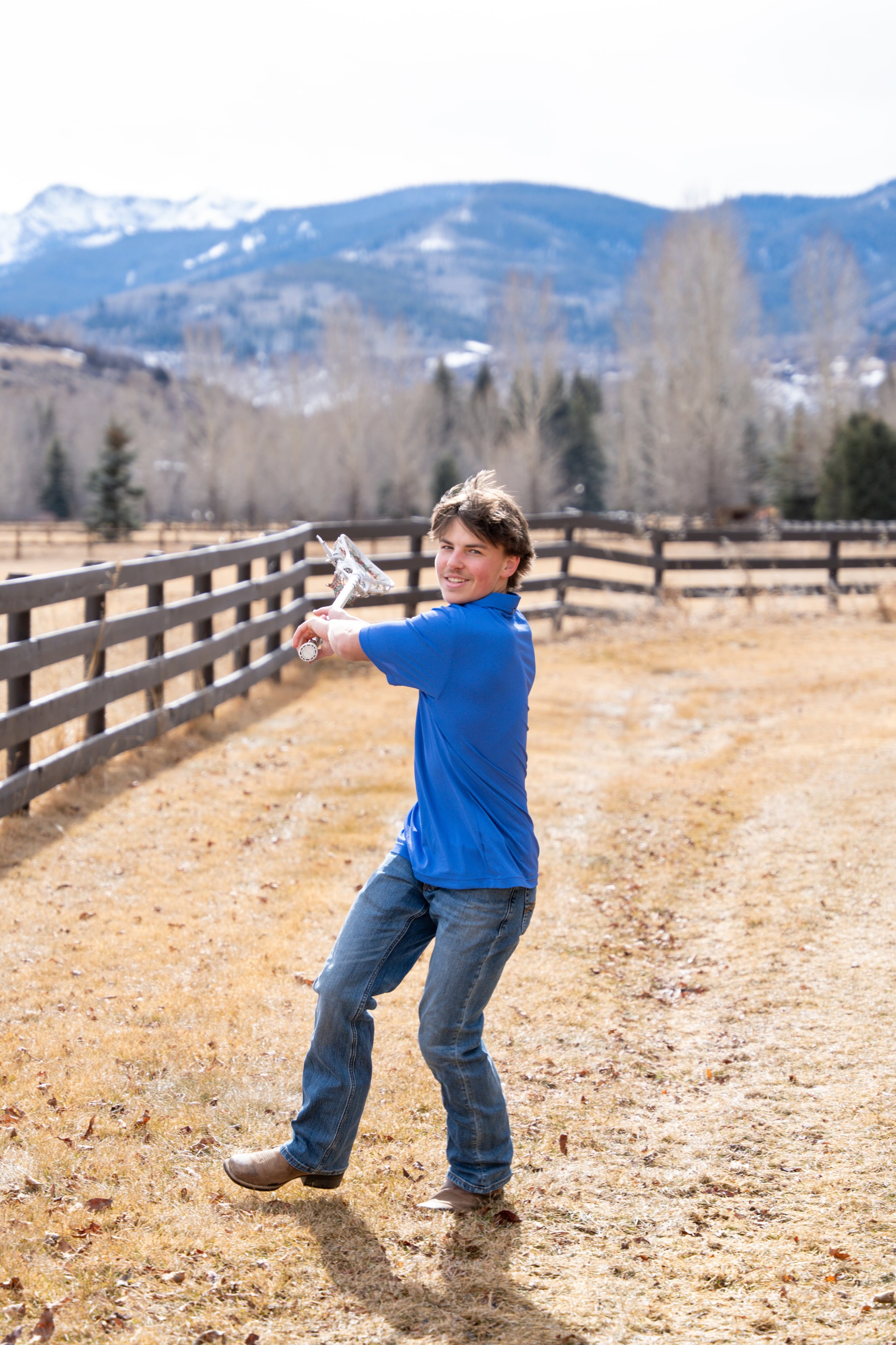 Teagan swinging a lacrosse stick along the fence line
