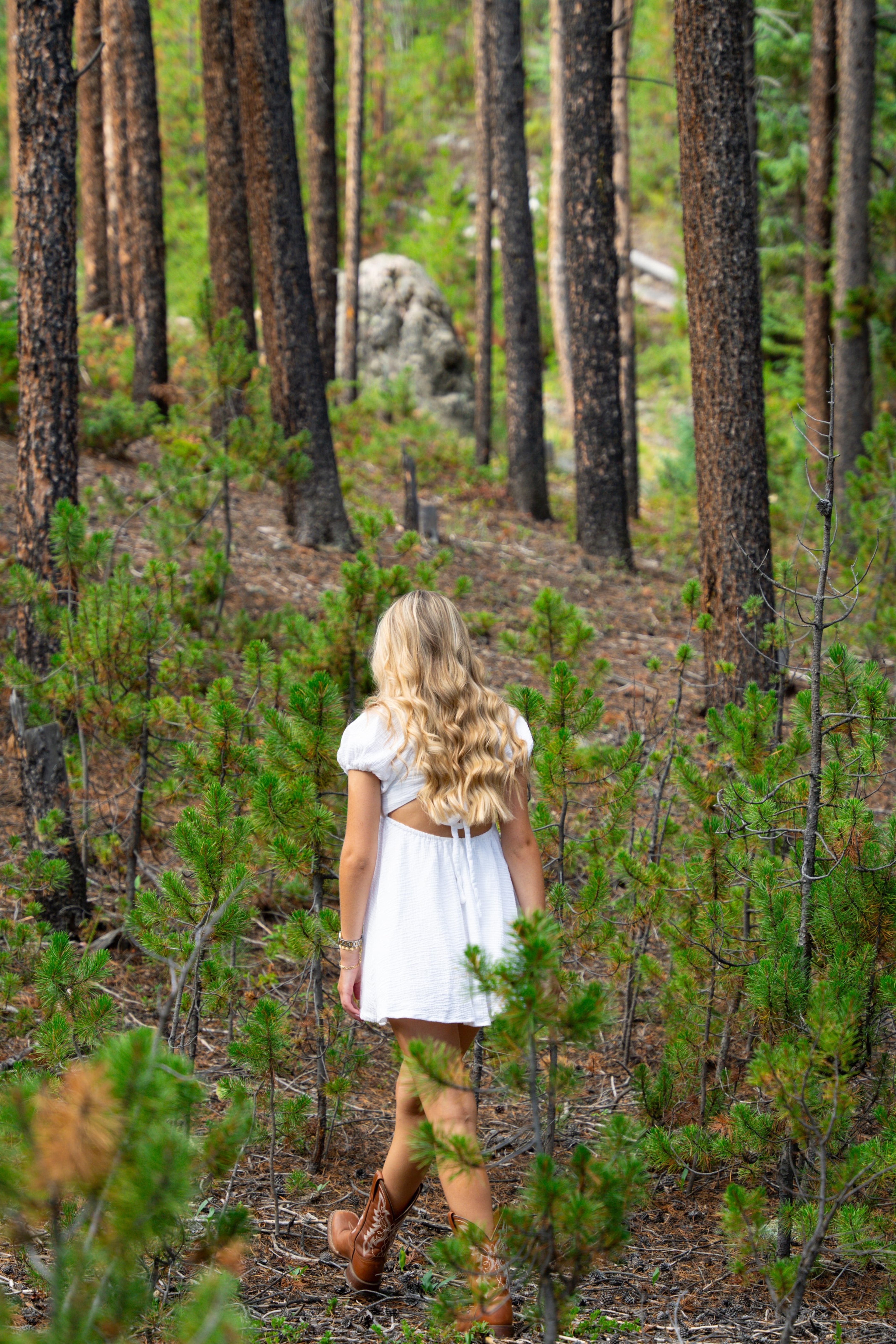 Caleigh walking between tall pine trees