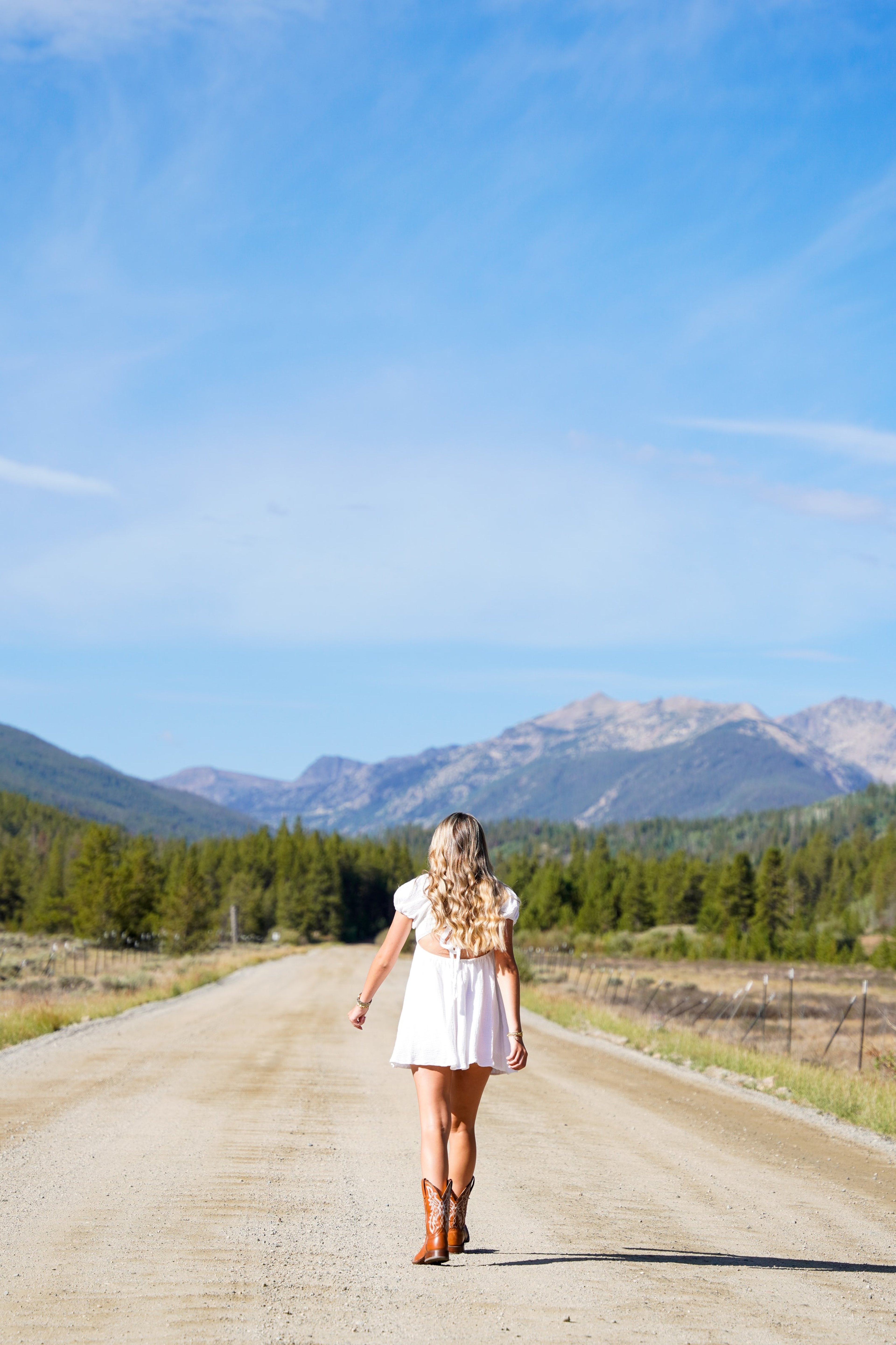 Caleigh walking away along a dirt road toward the mountains