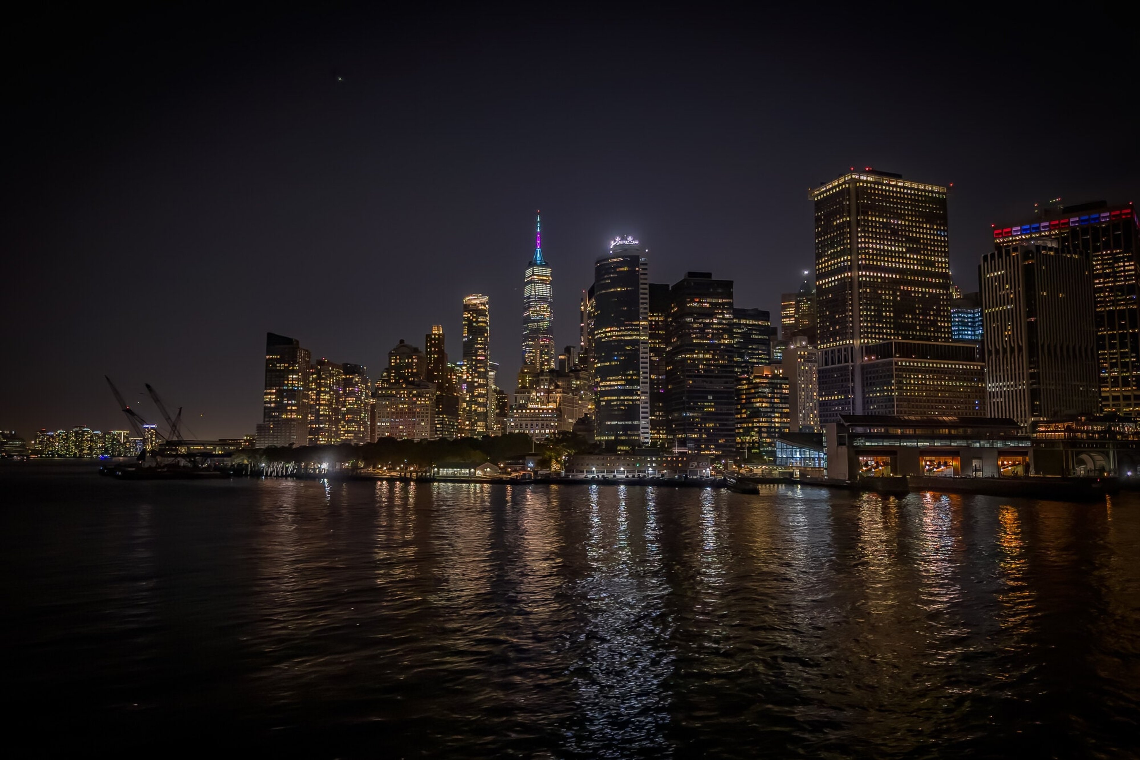 The lower Manhattan skyline burning across the East River at night