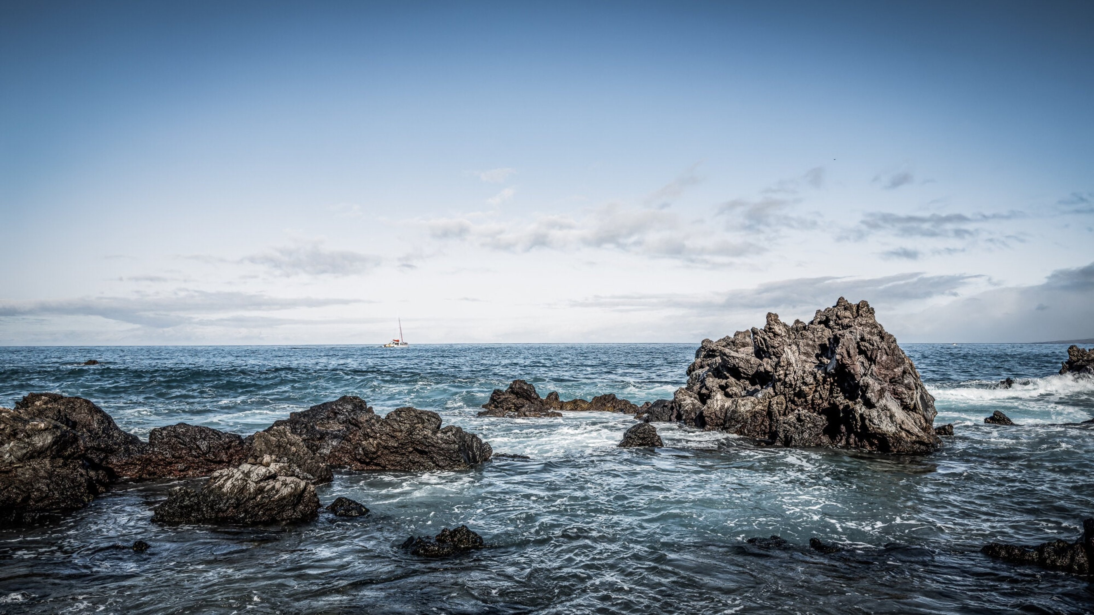 Surf breaking around sea rocks under moving clouds, Hawaii