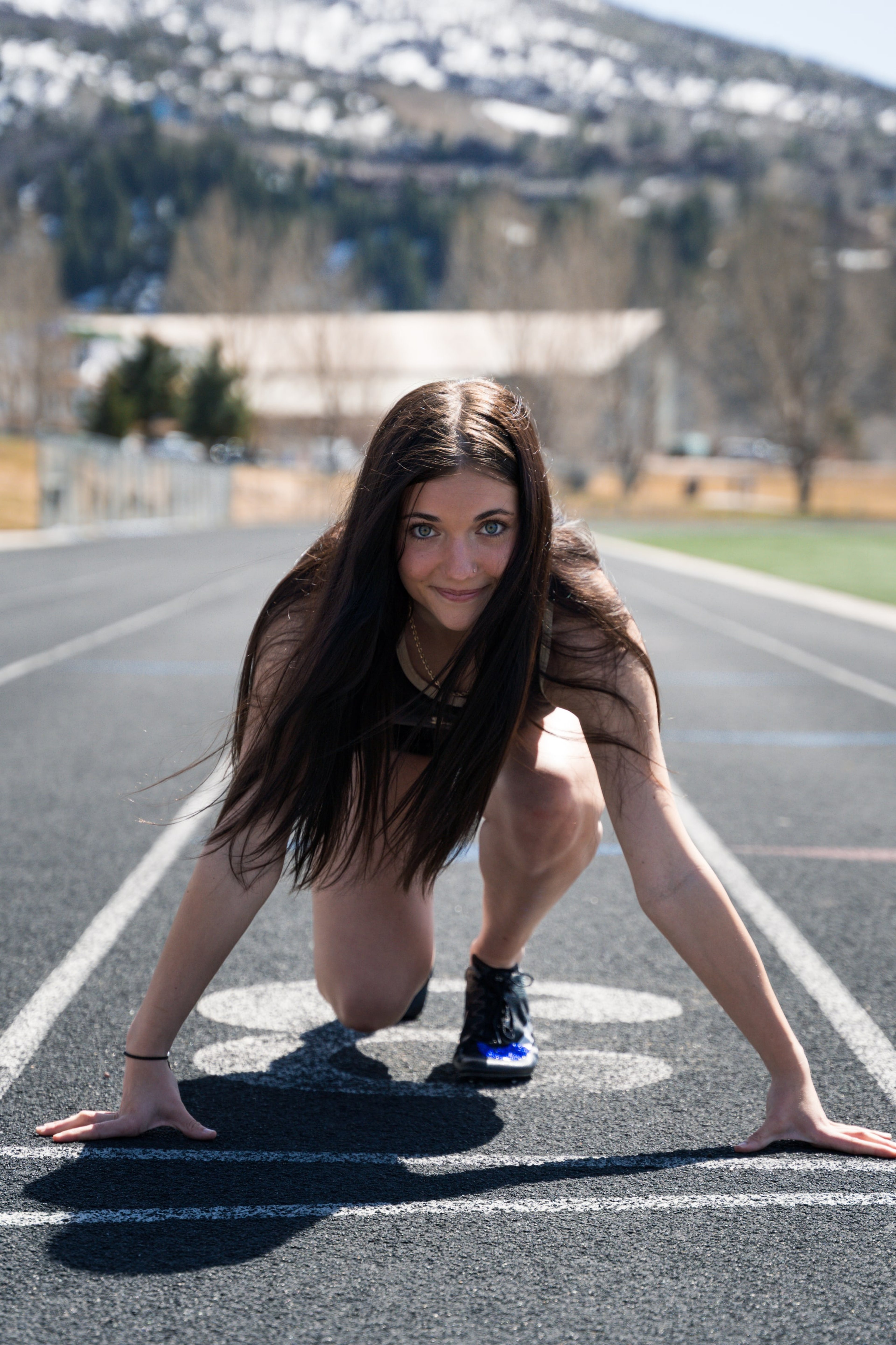 Lucy crouched in the blocks, snow-dusted ridge beyond the track
