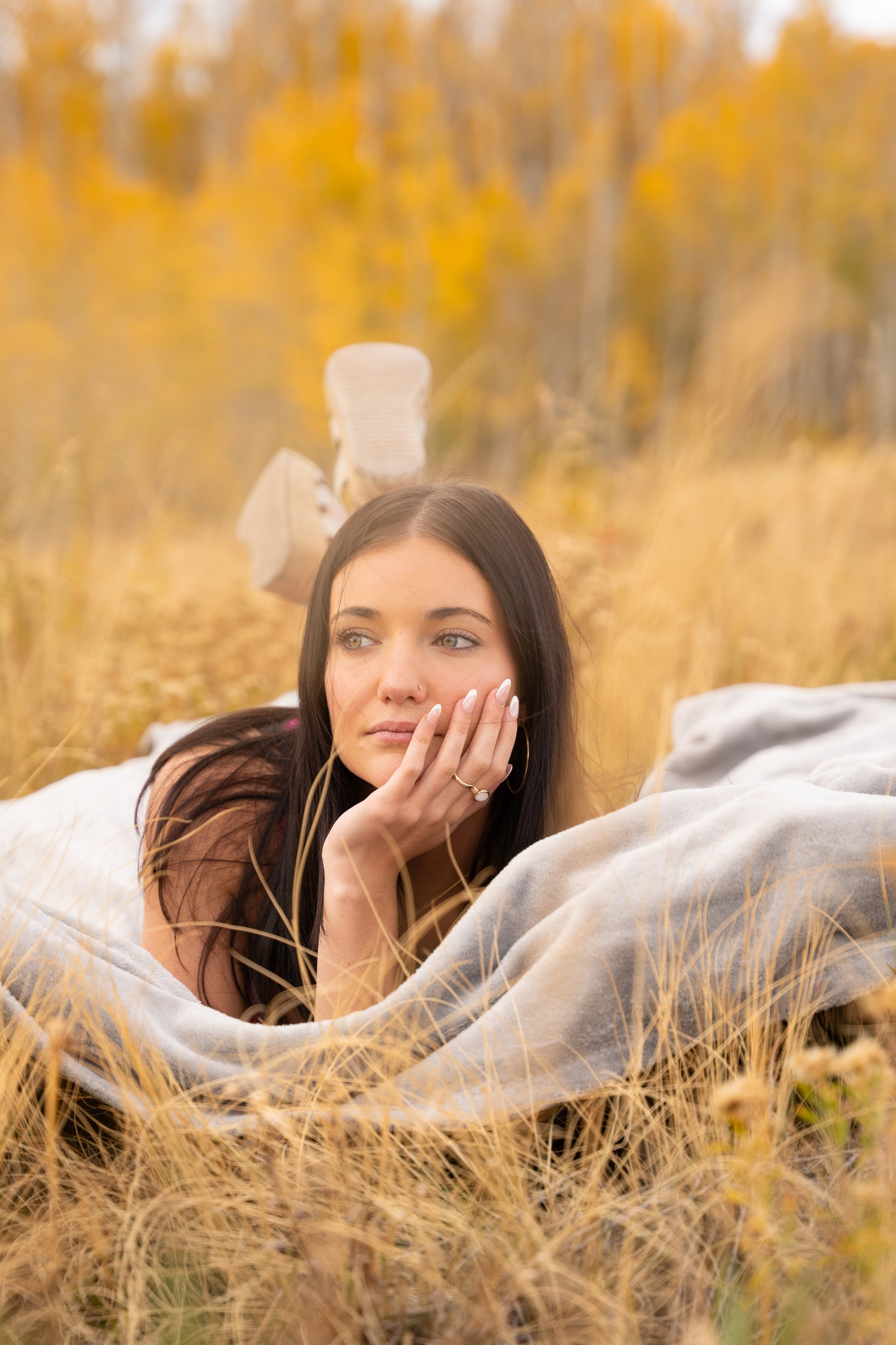 Lucy lying on a blanket in golden grass, chin on her hand