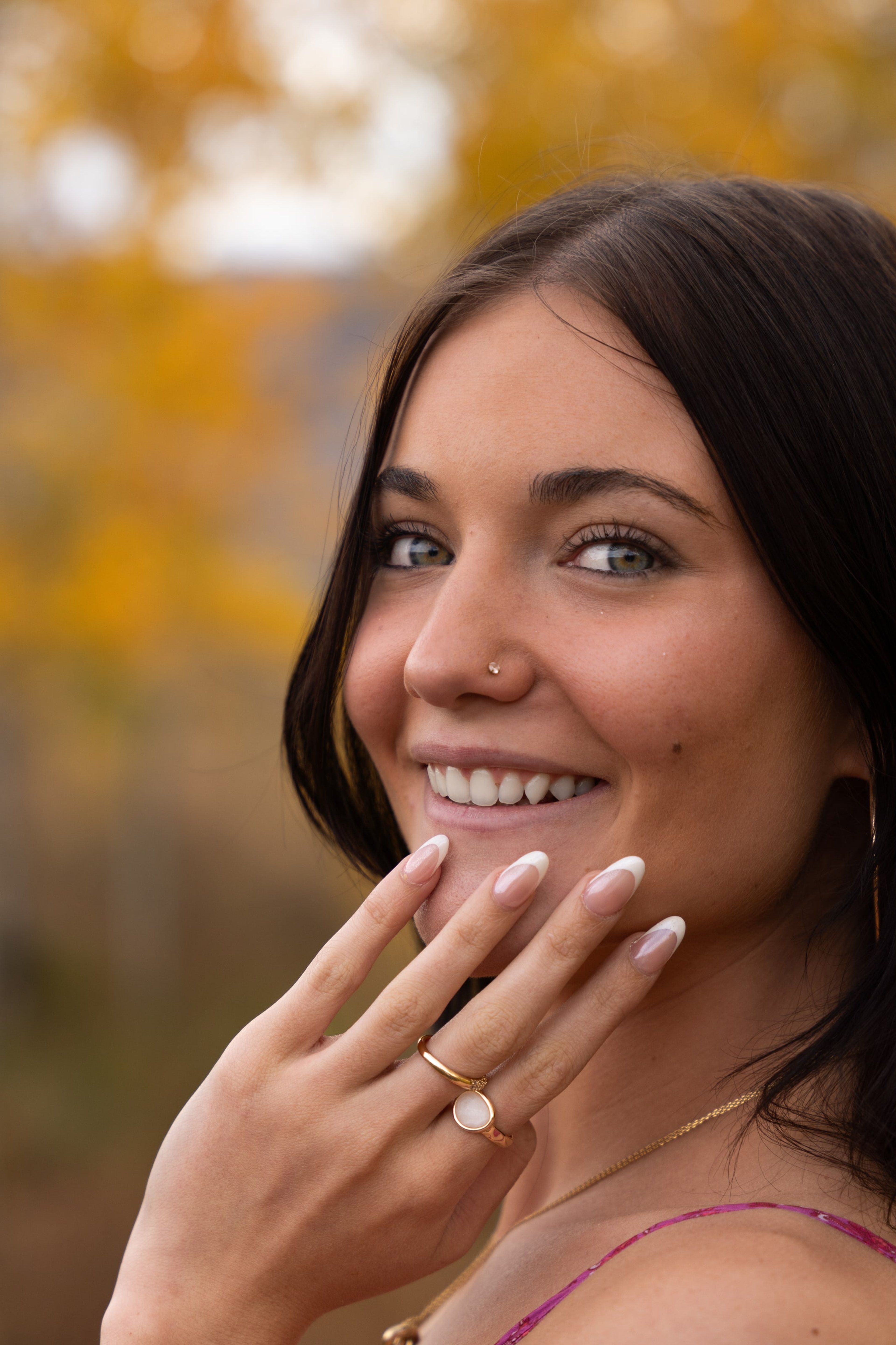 Lucy laughing close-up among golden aspens, hand near her face