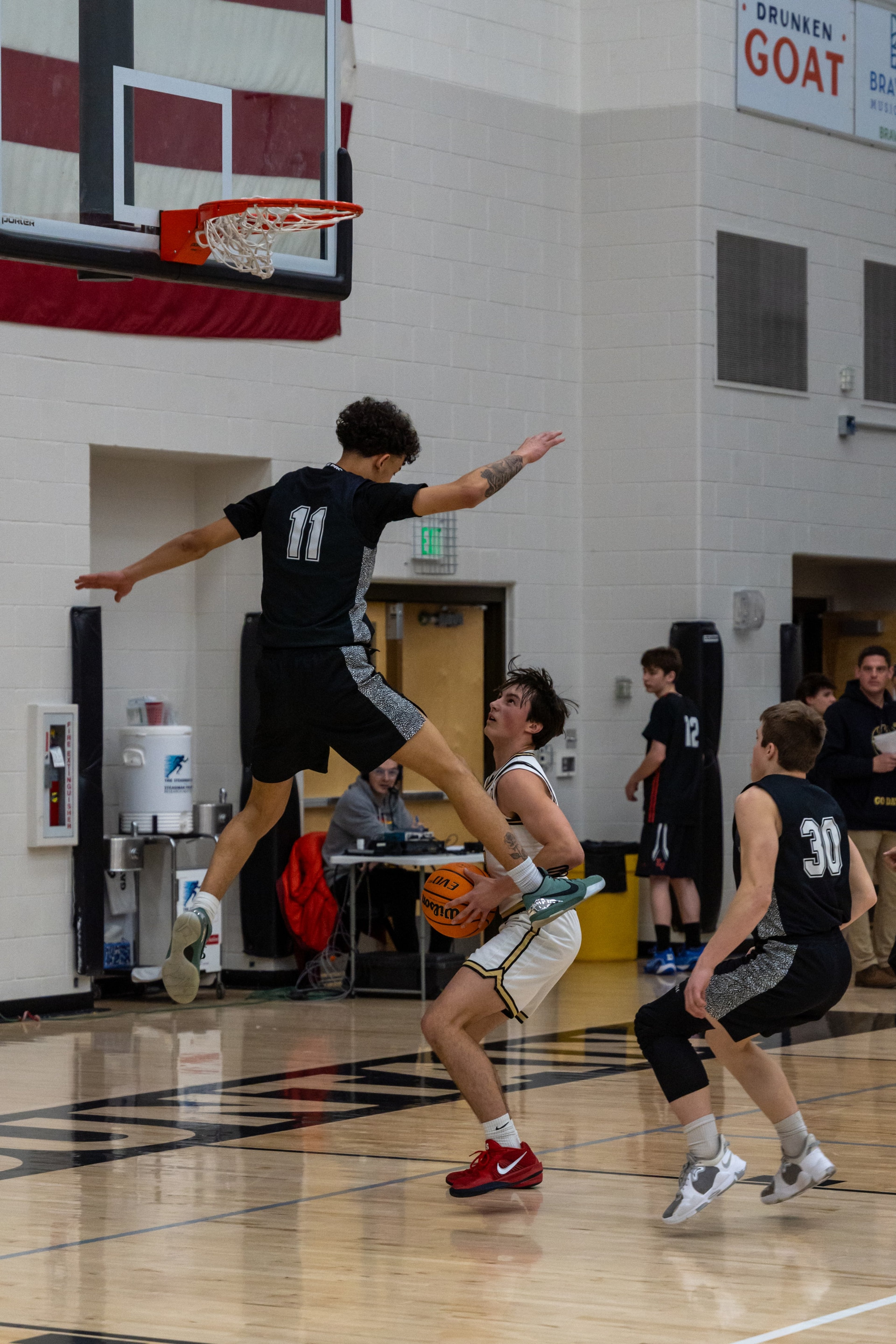 A defender leaps as the ball handler holds his ground beneath the basket