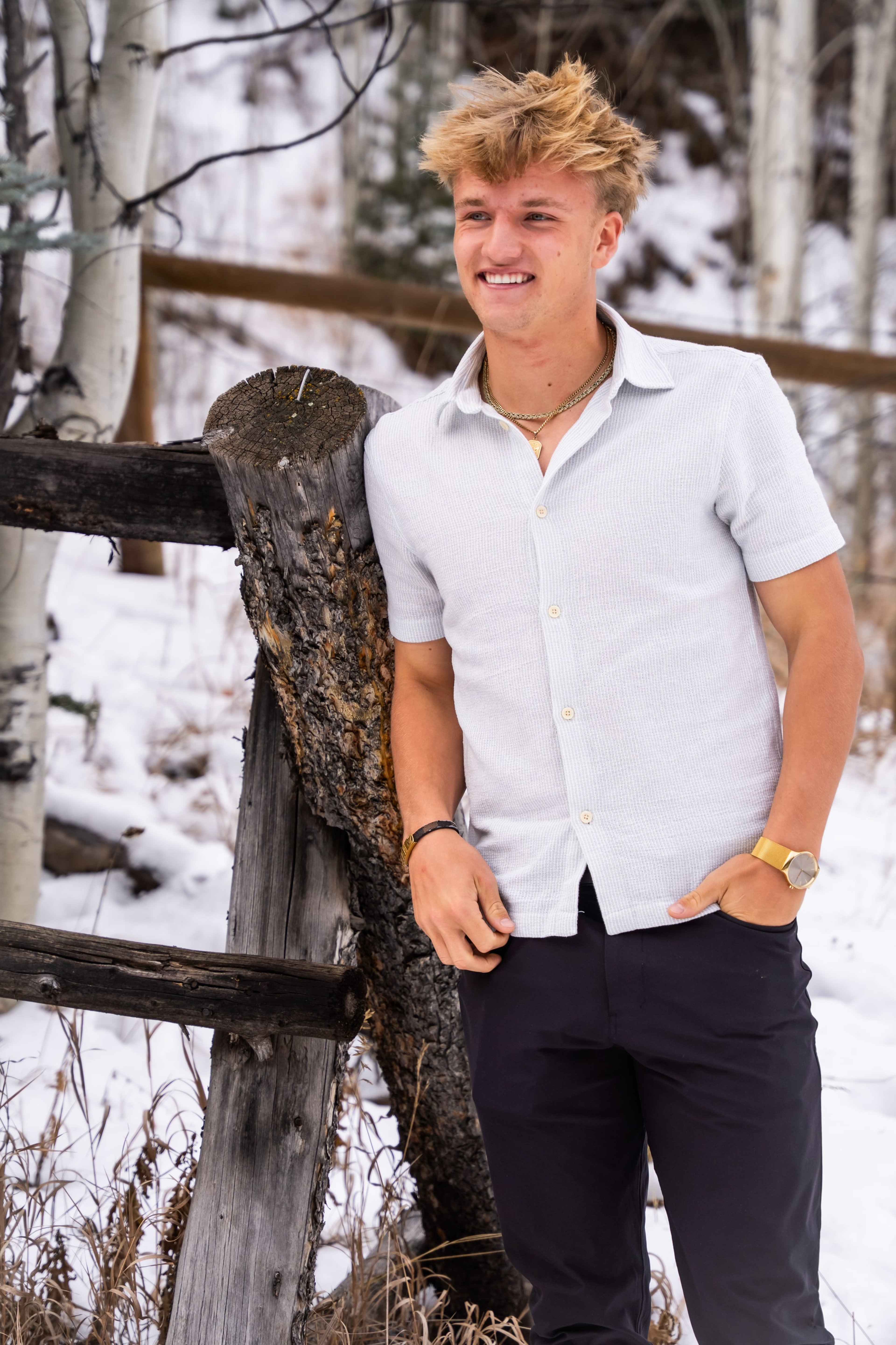 Jakob at the fence with hands in pockets, aspens behind