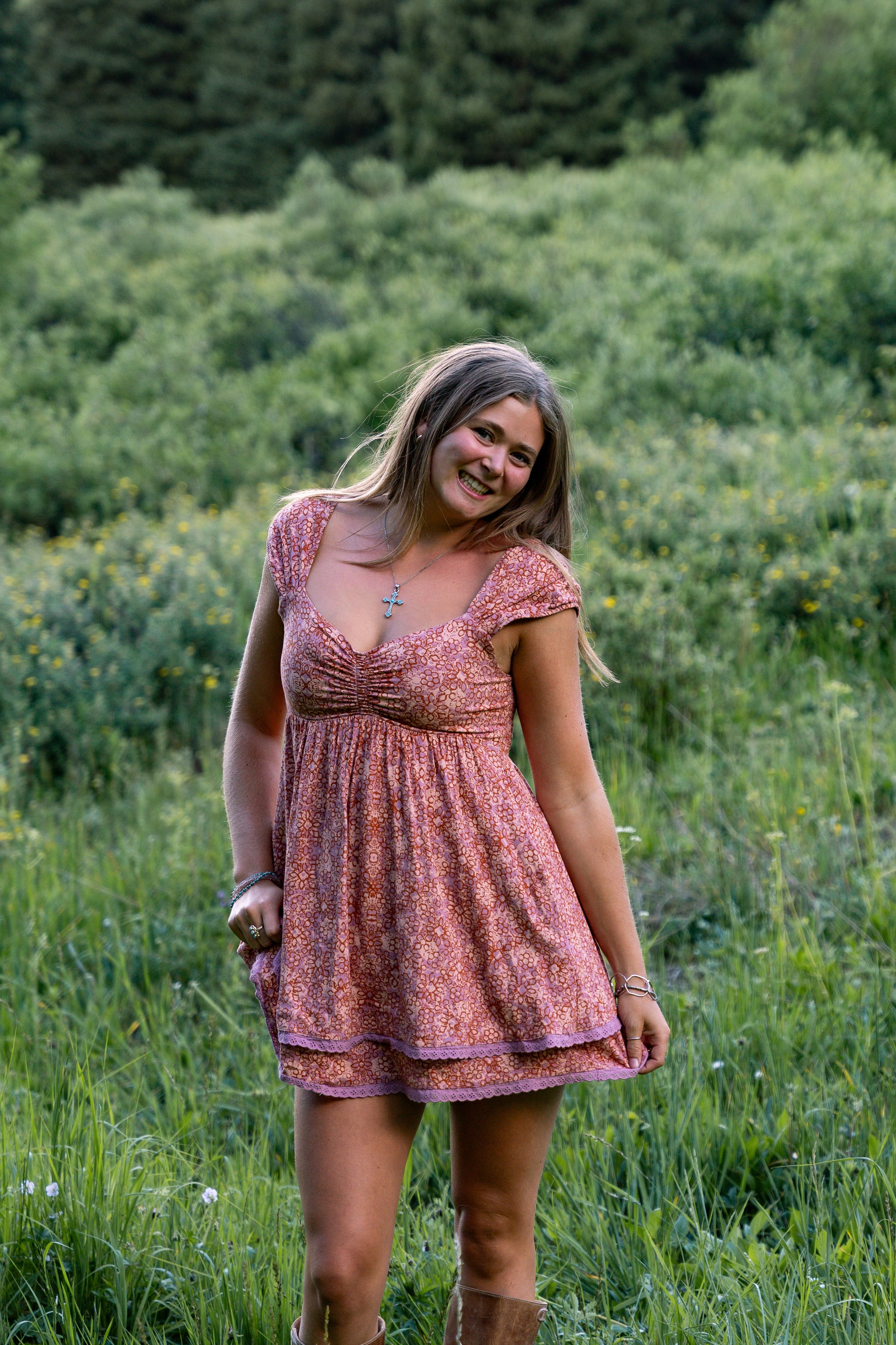 A girl in a pink dress laughing among the daisies