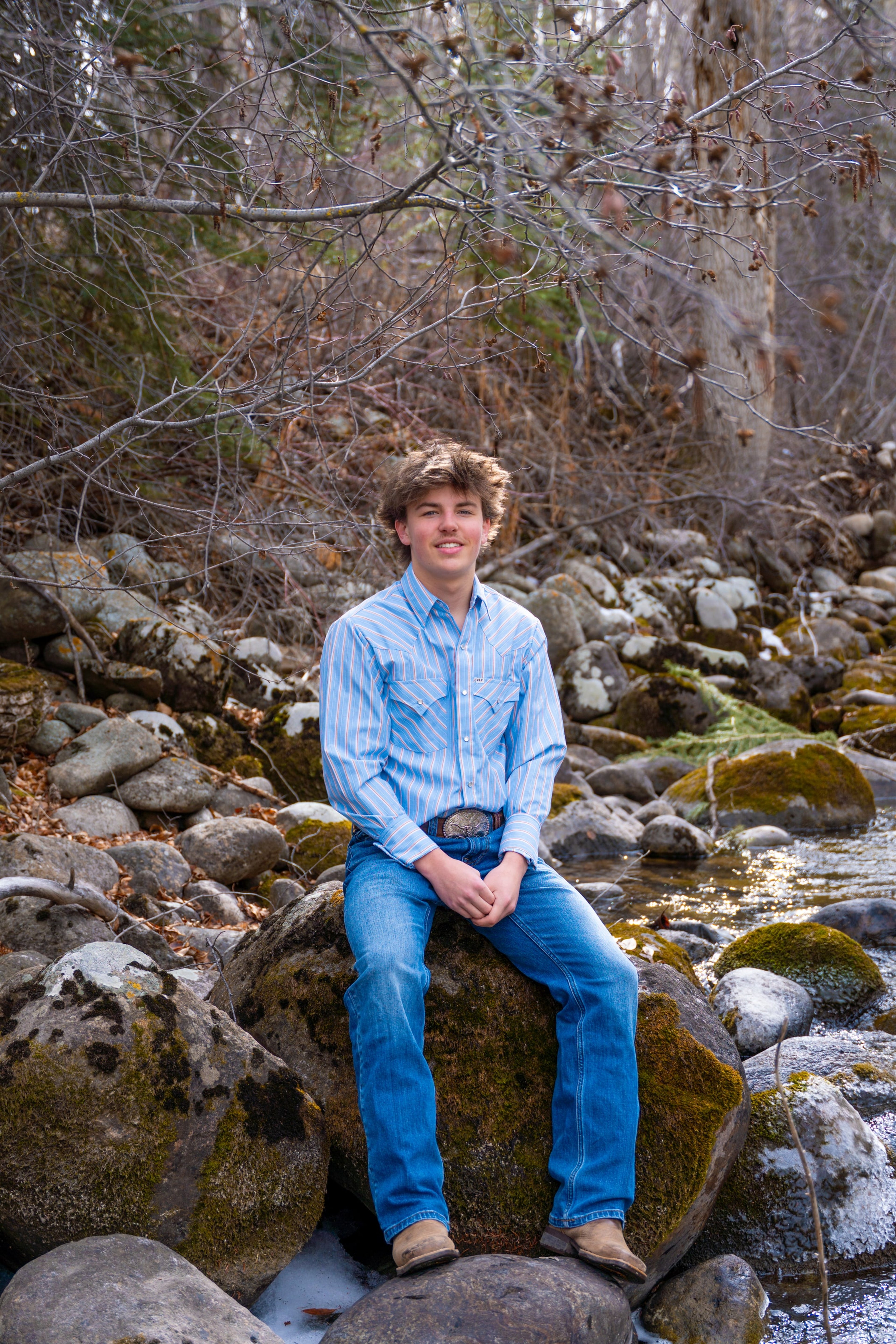 Teagan seated on a mossy boulder beside the creek