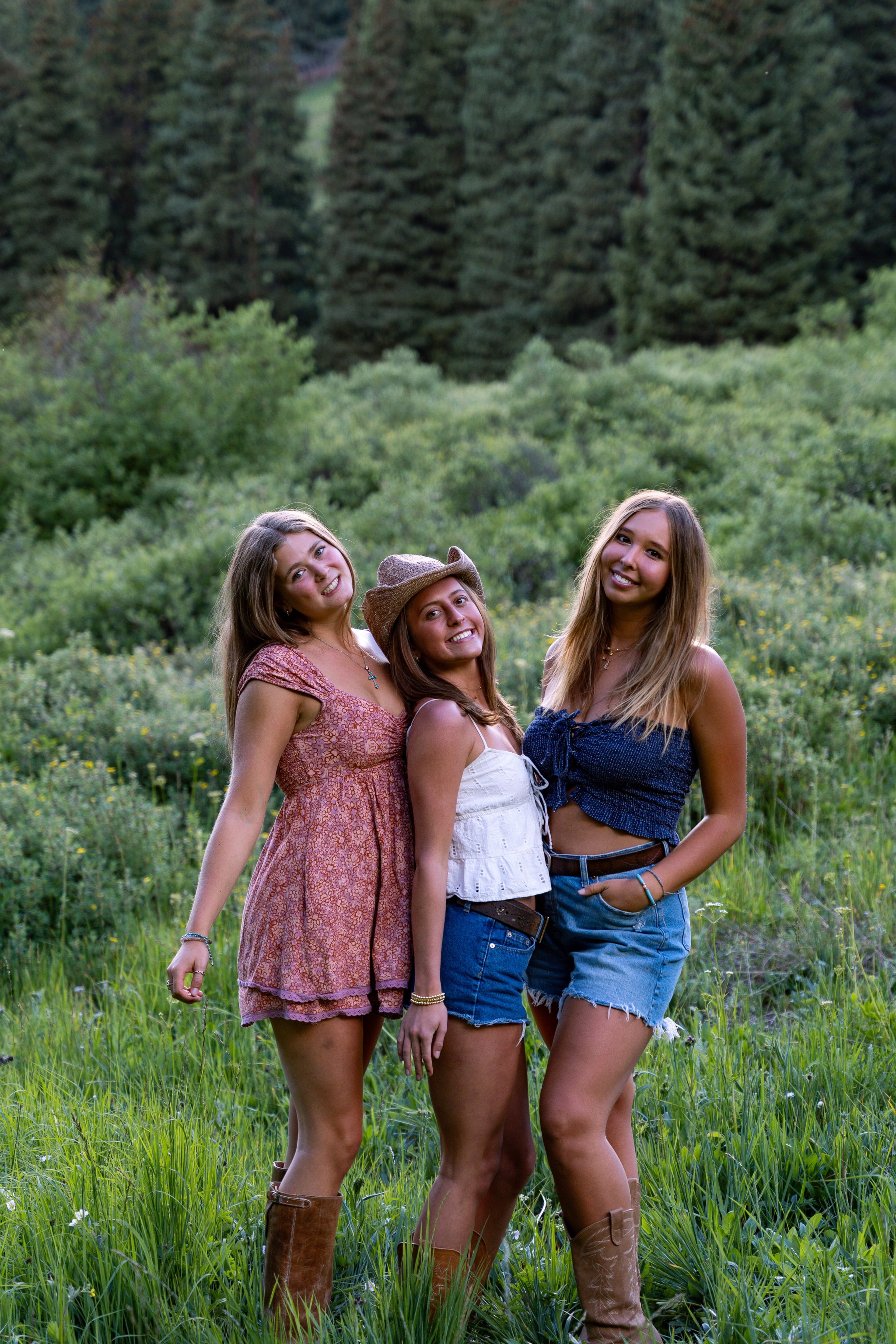 Three friends leaning together laughing in the meadow