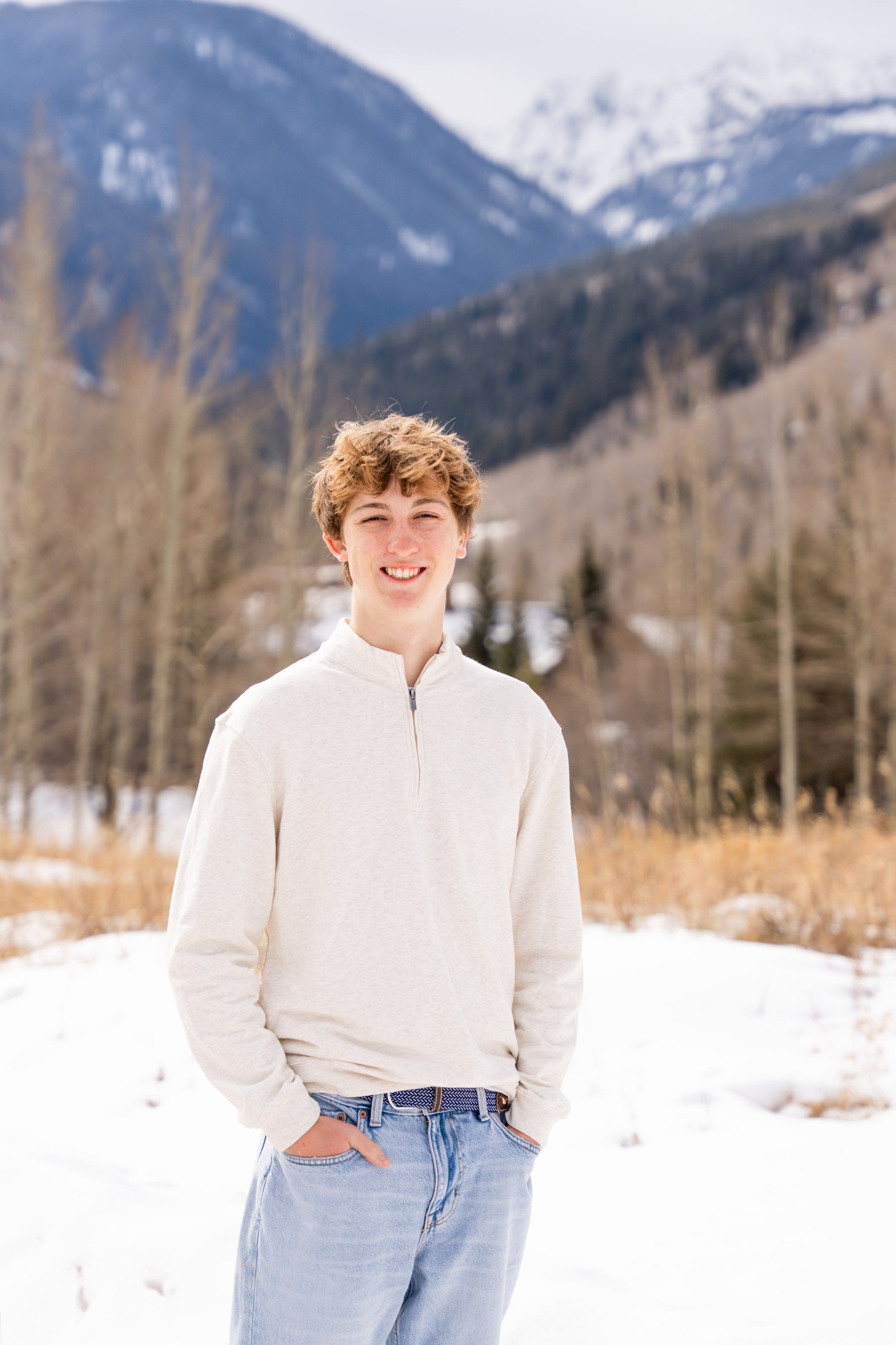 Wake in a cream quarter-zip standing in snowy aspens