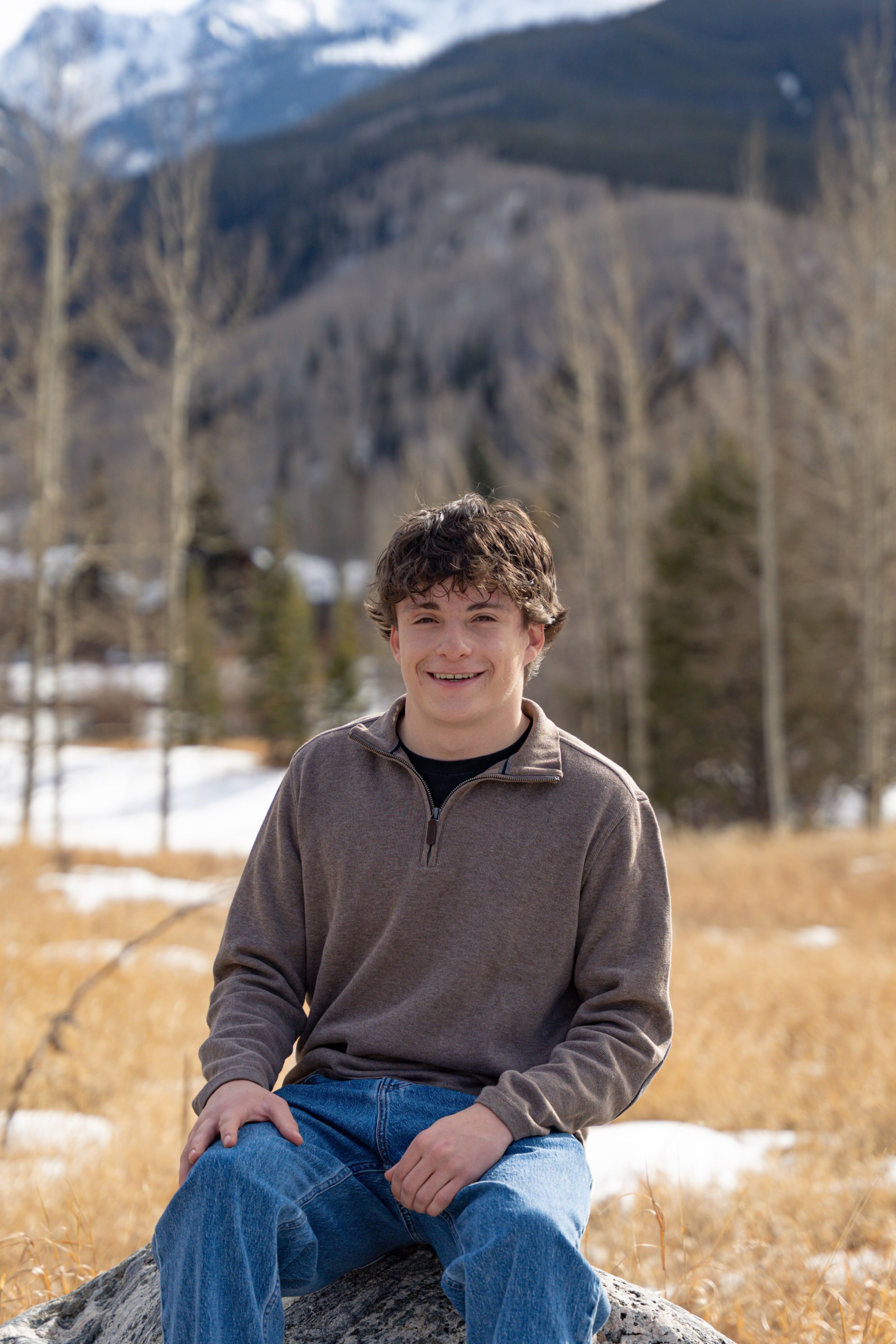 Luca seated on a rock at the meadow's edge