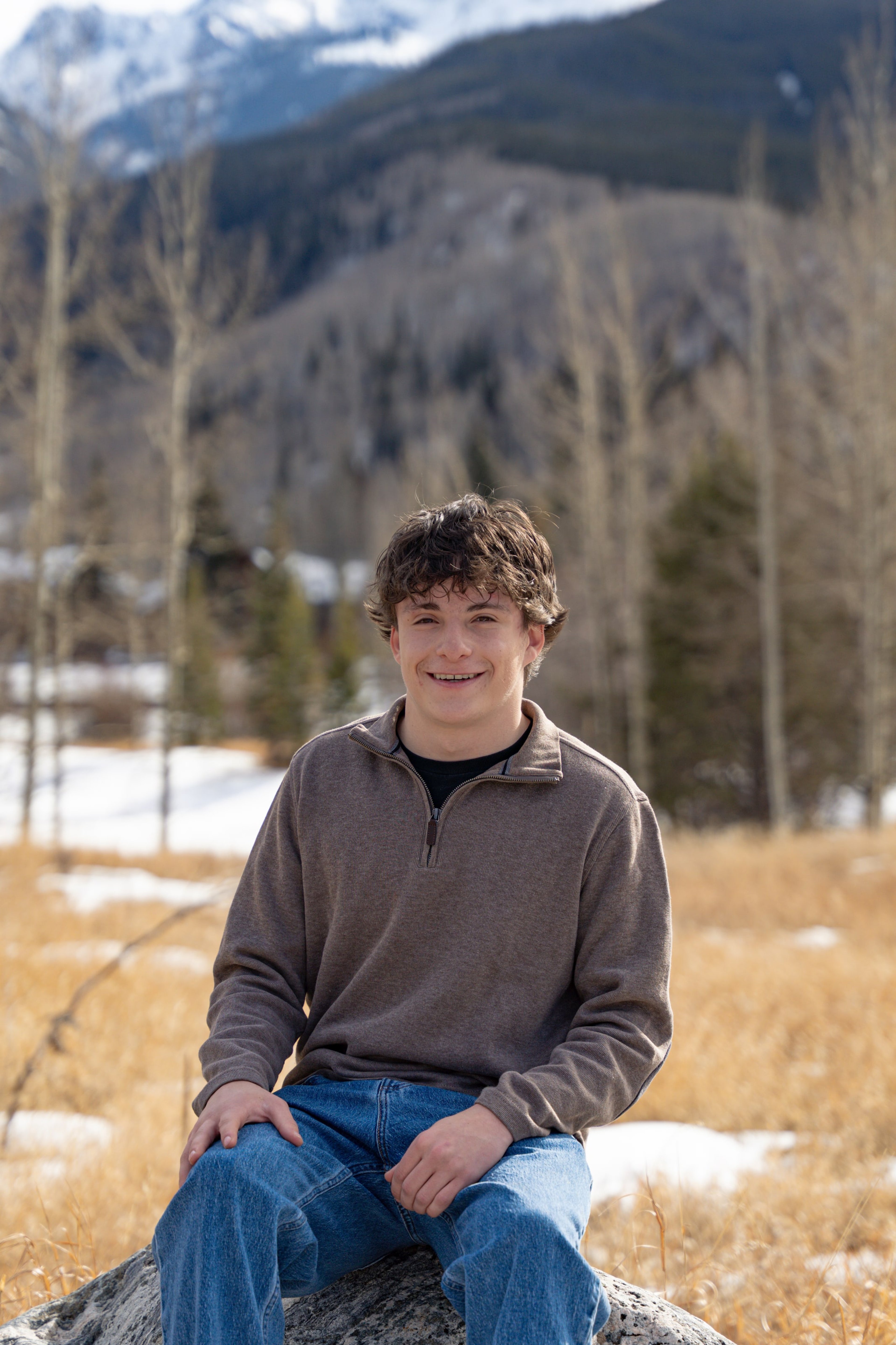 Luca seated on a rock at the meadow's edge