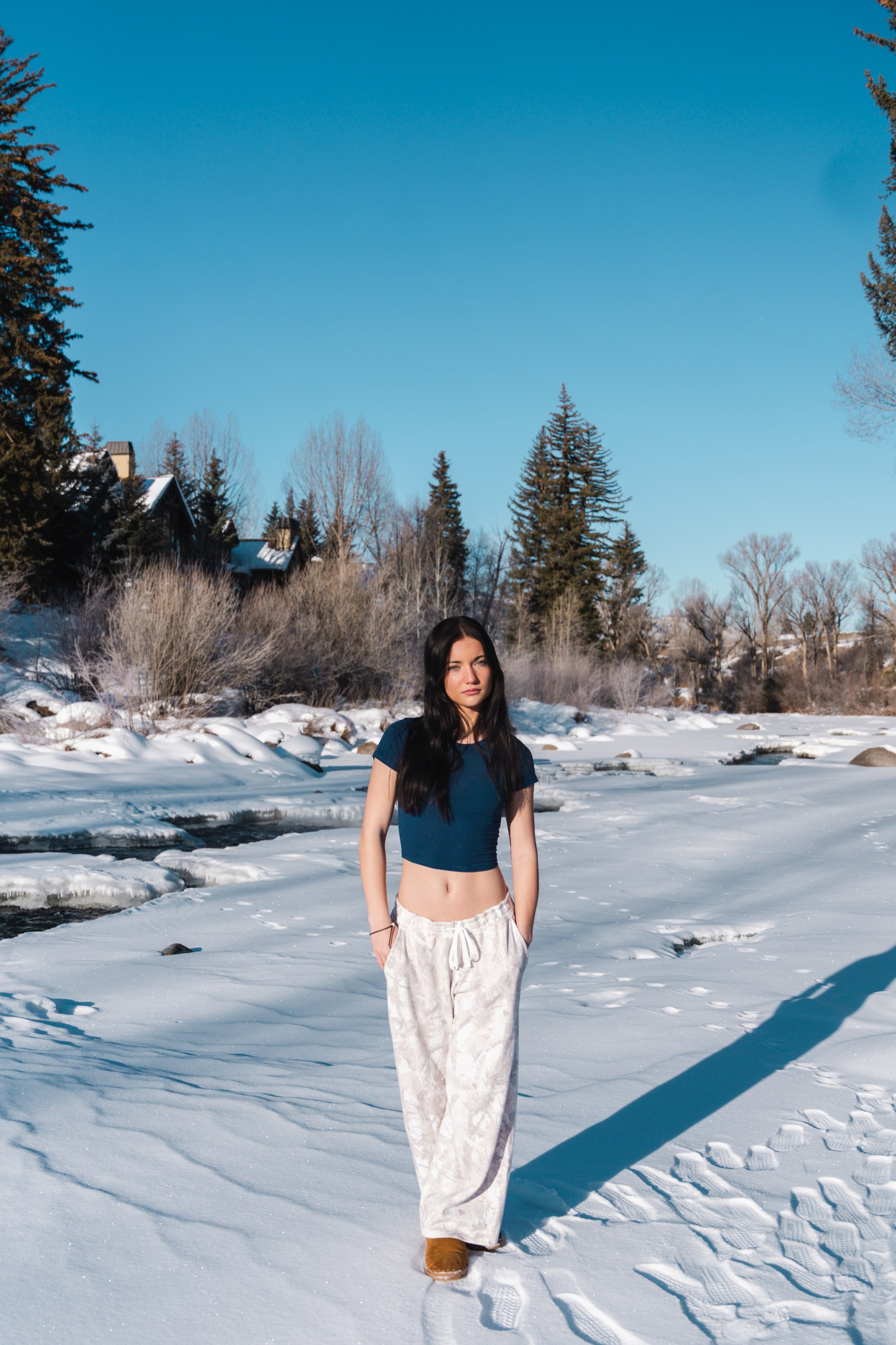 Lucy standing small on wind-carved snow along the winter river