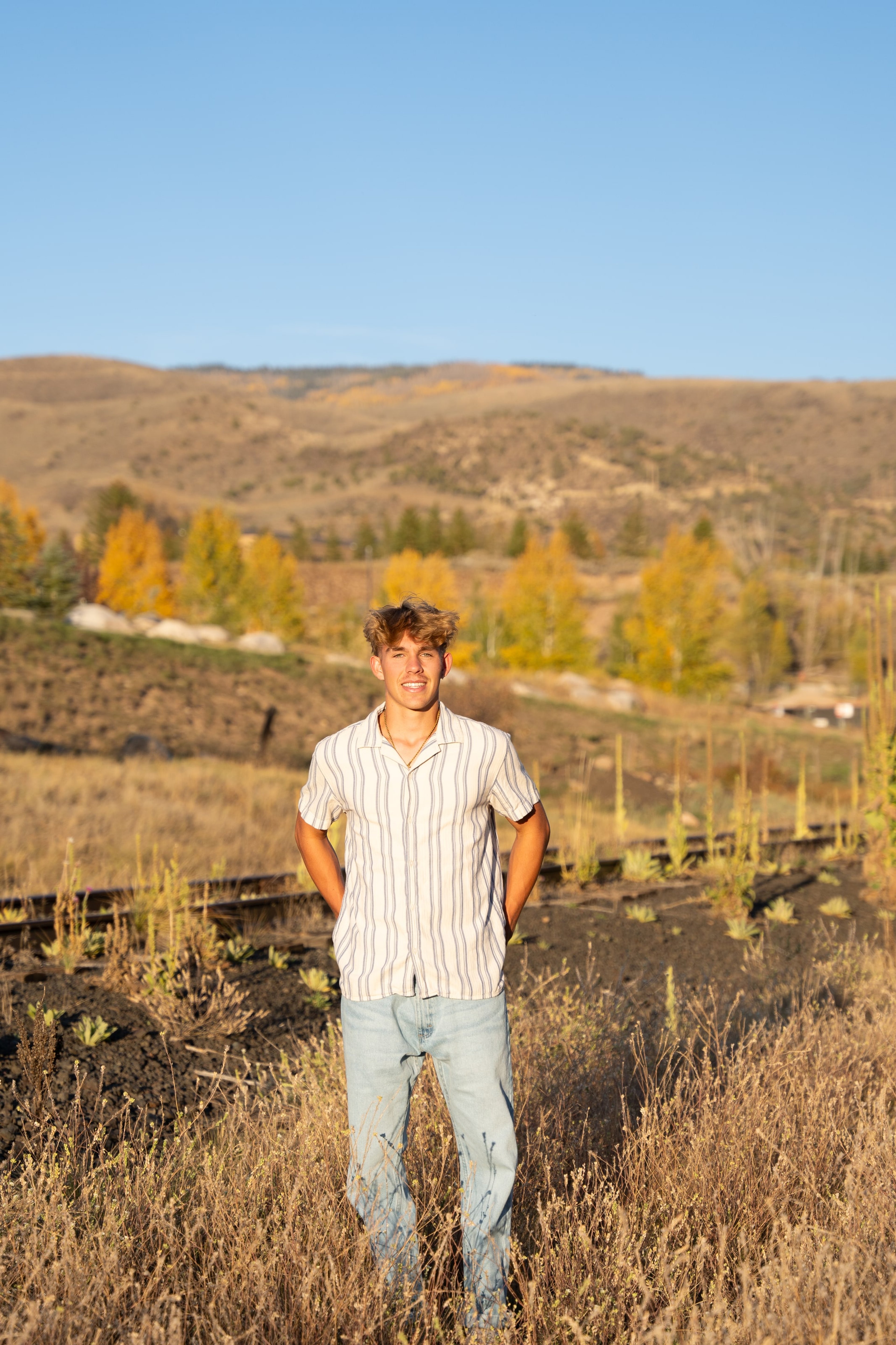 Wyat standing in dry scrub, gold trees dotting the hillside
