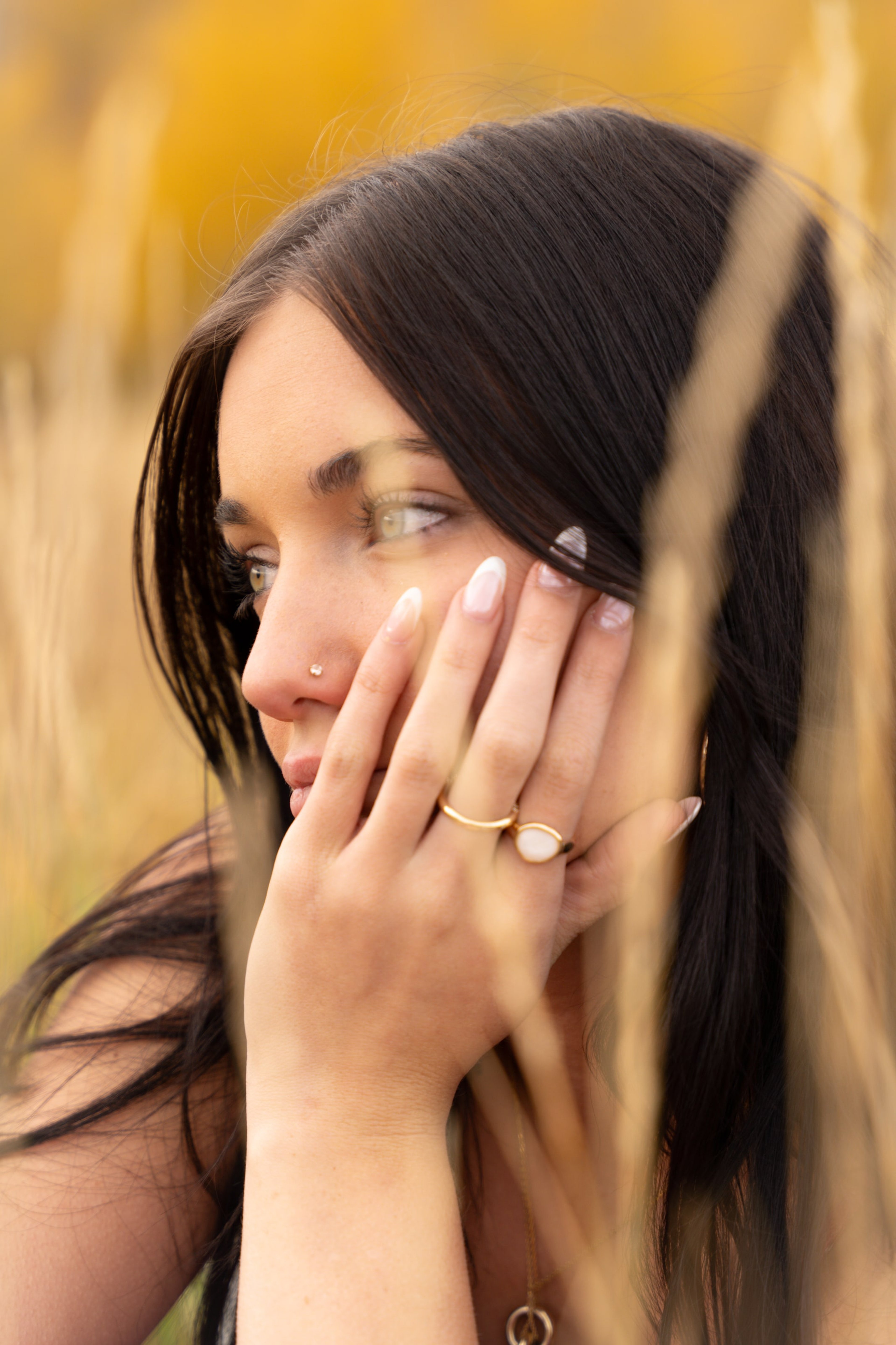 Close portrait of Lucy behind wisps of hair, autumn gold behind