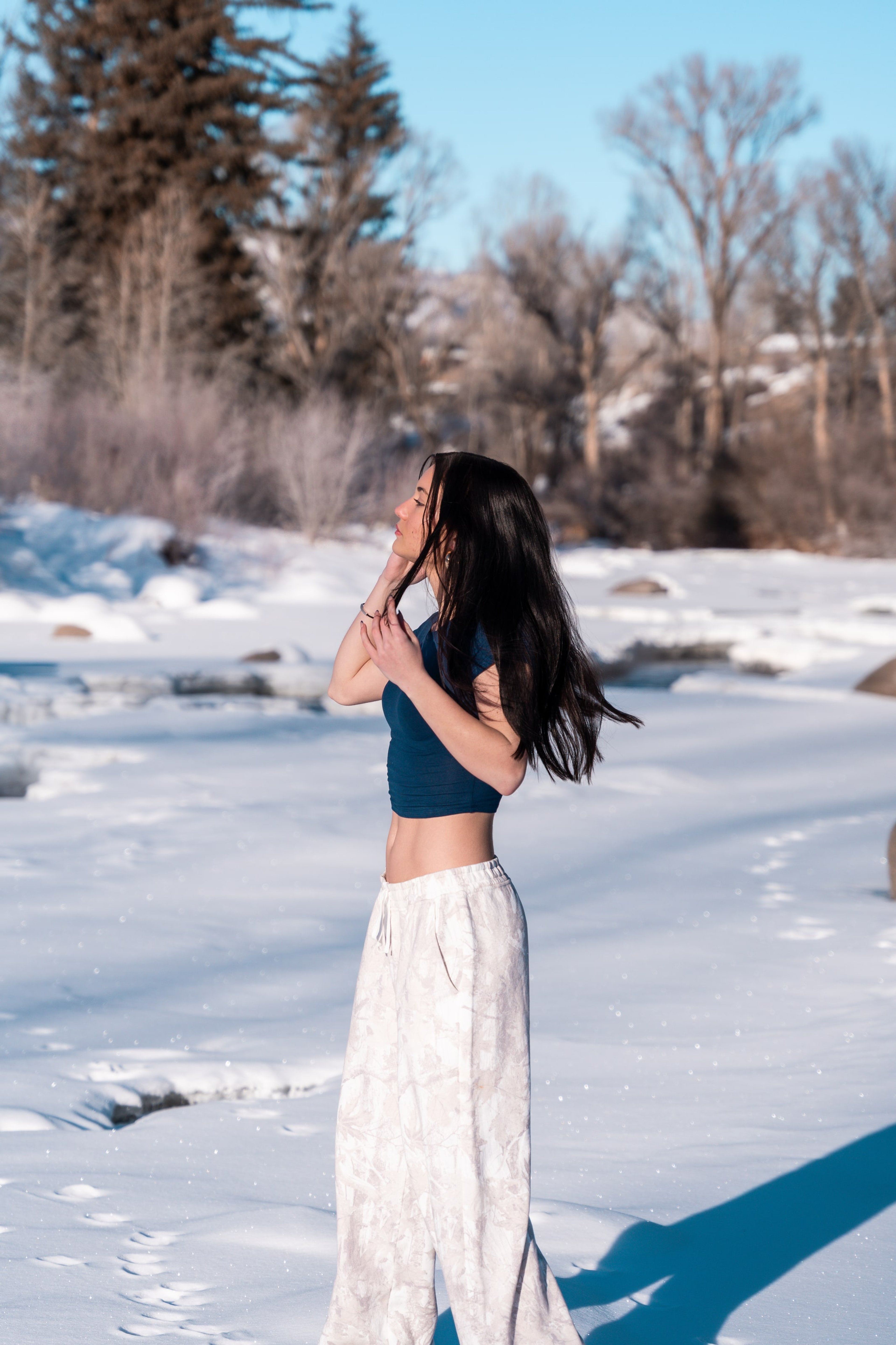 Lucy in profile brushing hair from her face above the frozen river