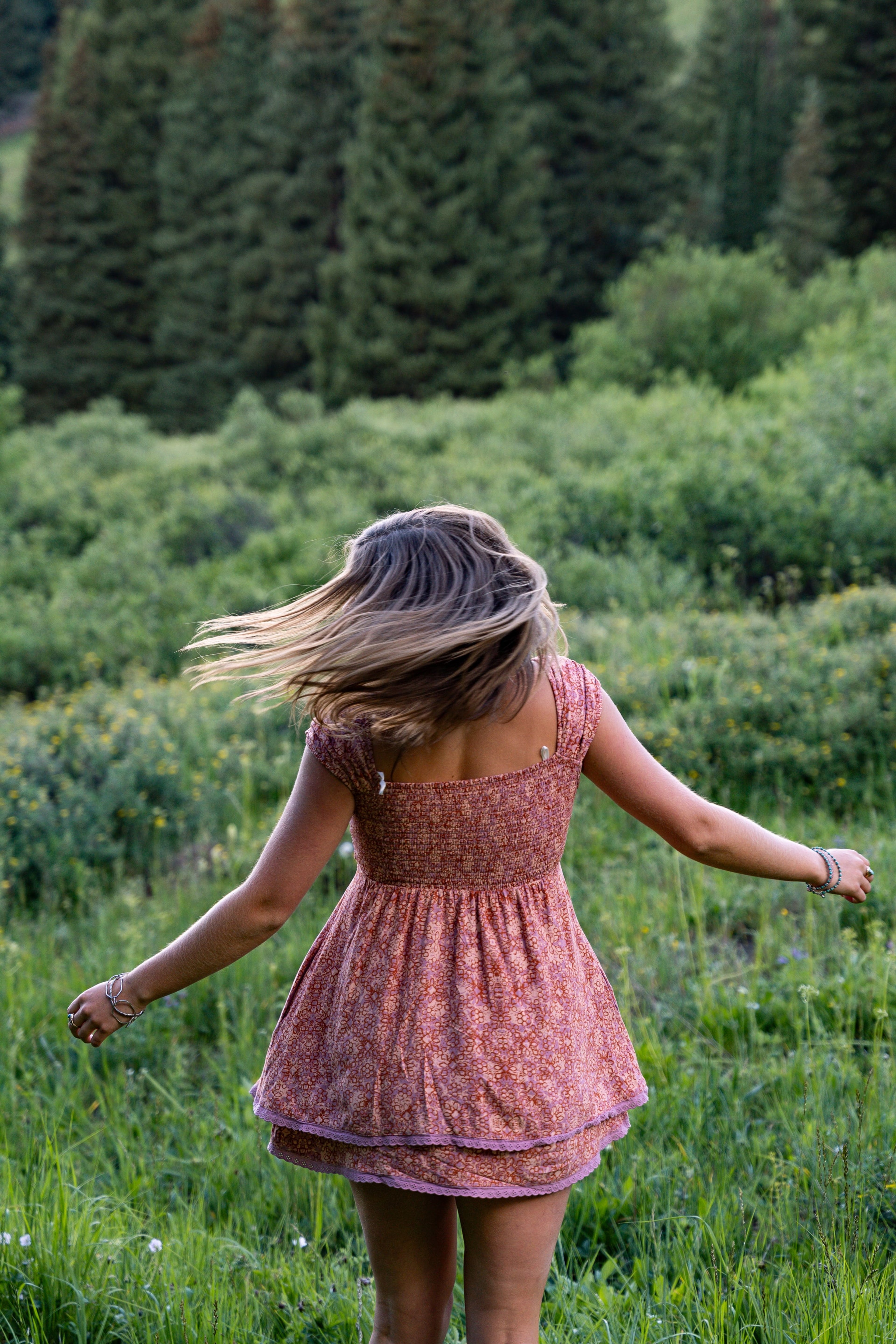 A pink sundress twirling away through the gold-green field