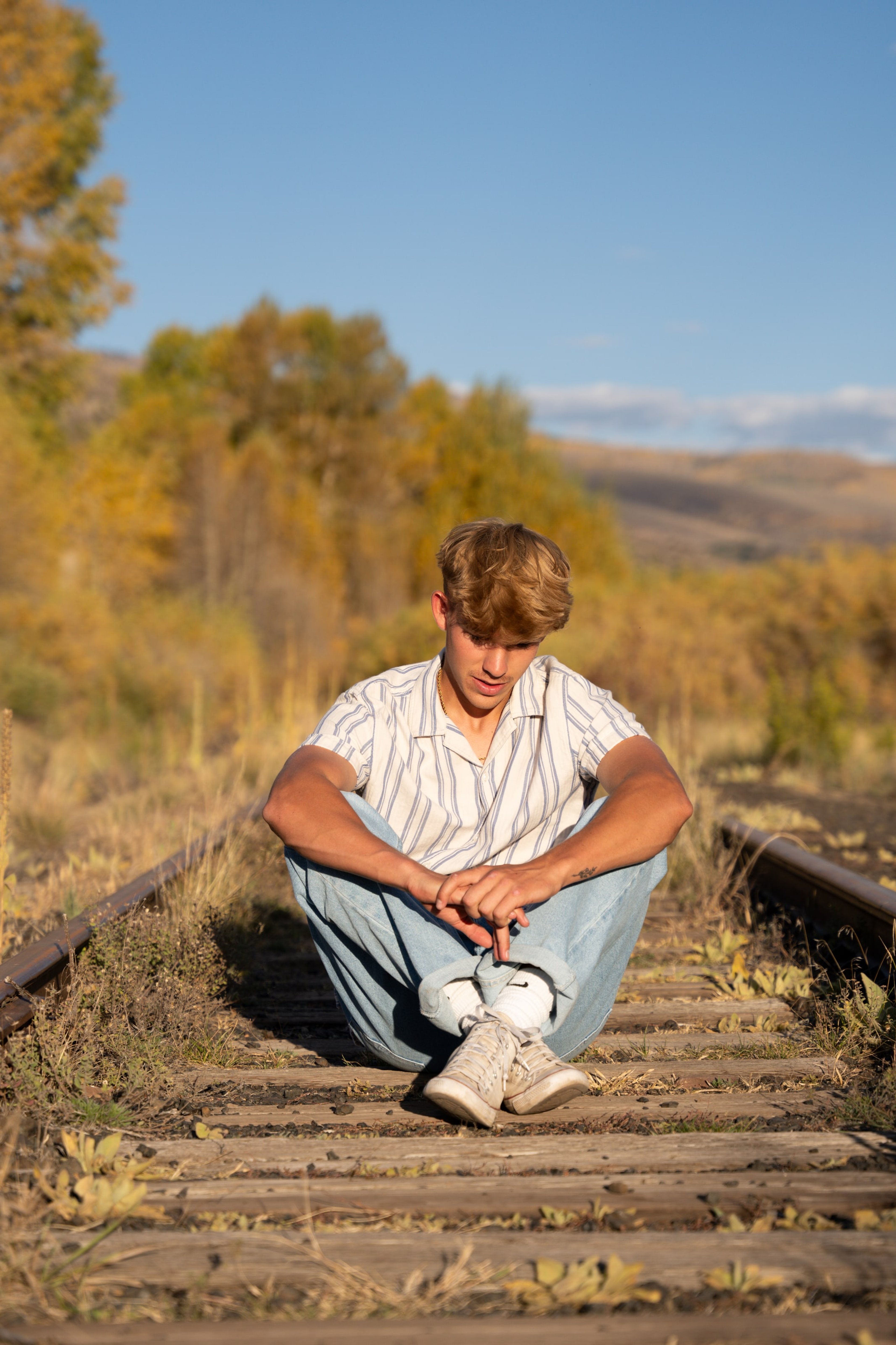 Wyat sitting on old railroad tracks, elbows on knees