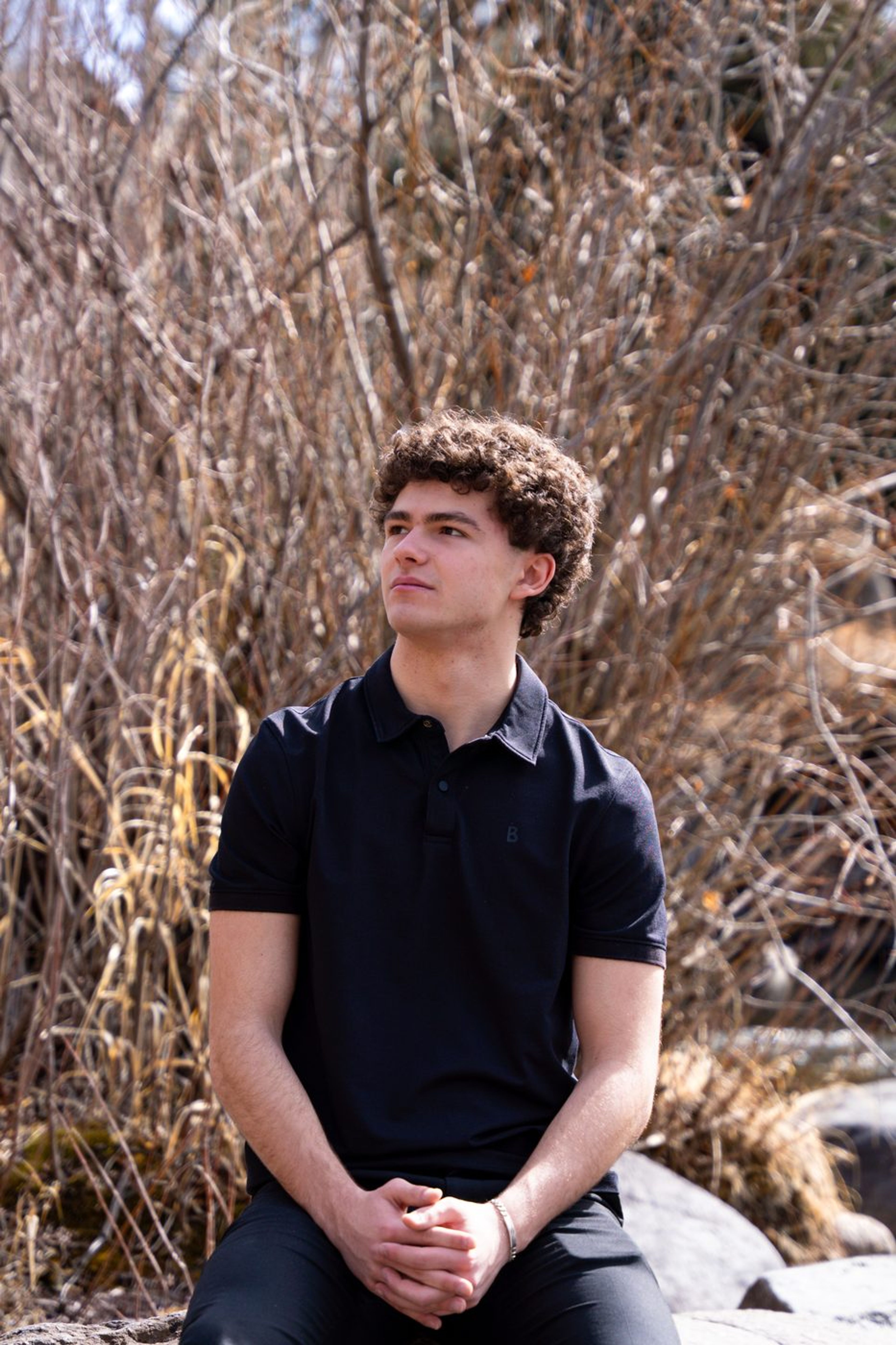 Contemplative senior portrait seated before winter brush