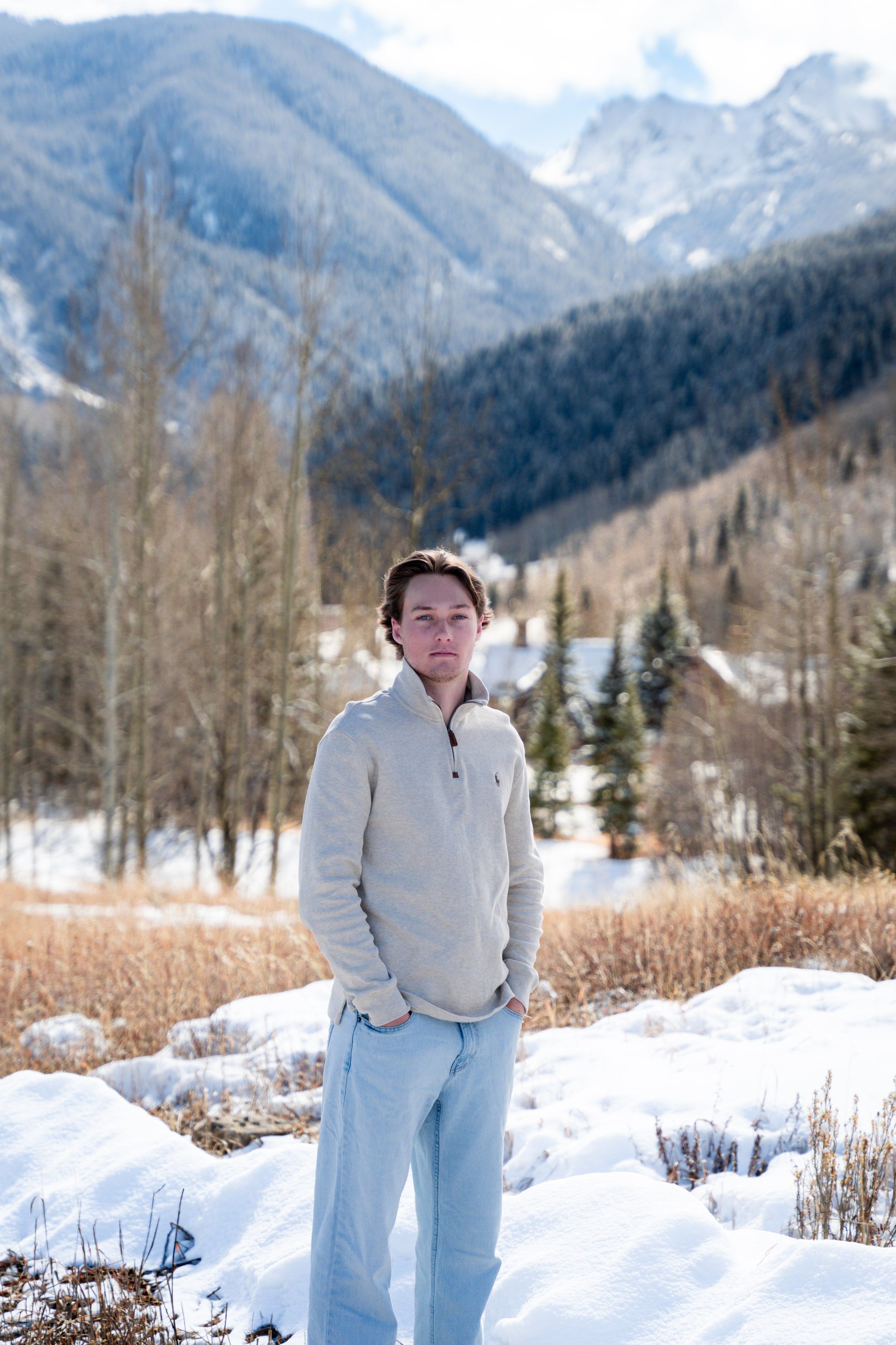 Caeden standing in snow and winter grass, peaks behind