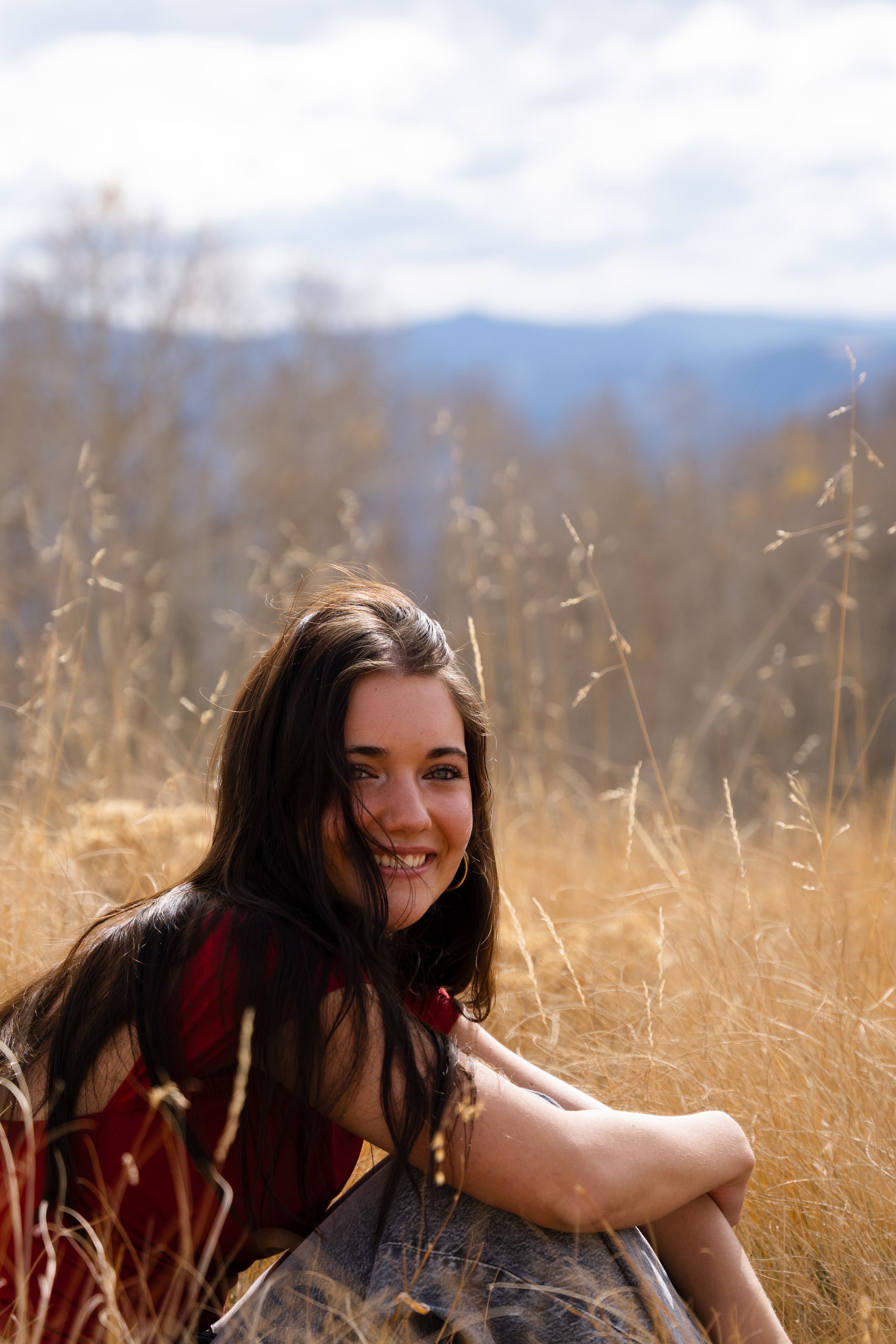 Lucy smiling in the gold grass, hair catching the low sun