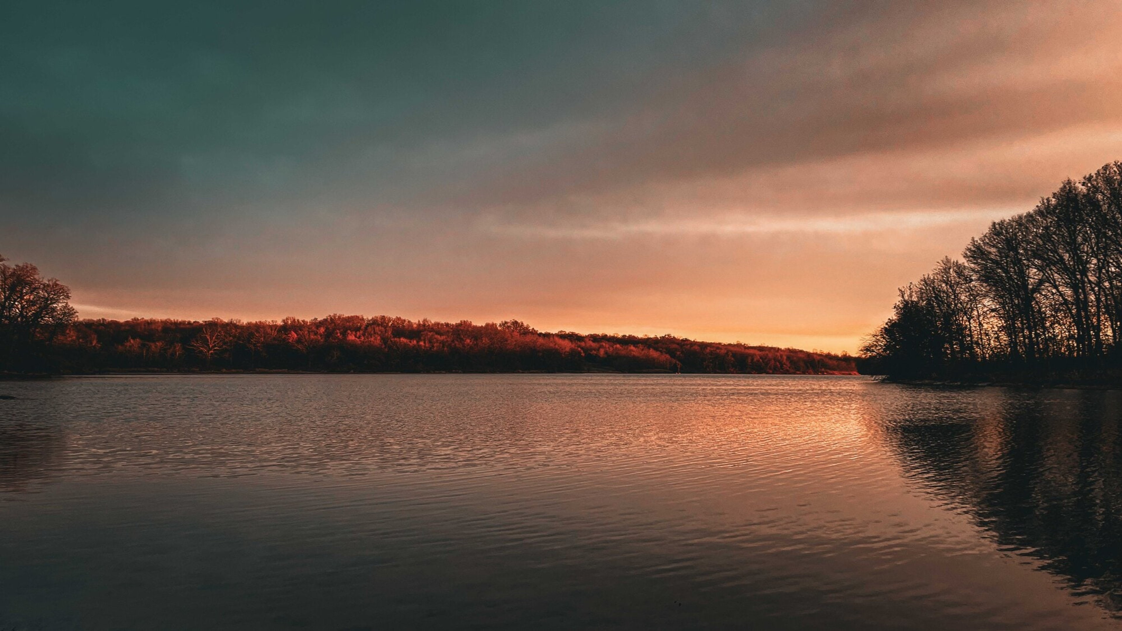 A burnt-orange sunset reflected in a still mountain lake