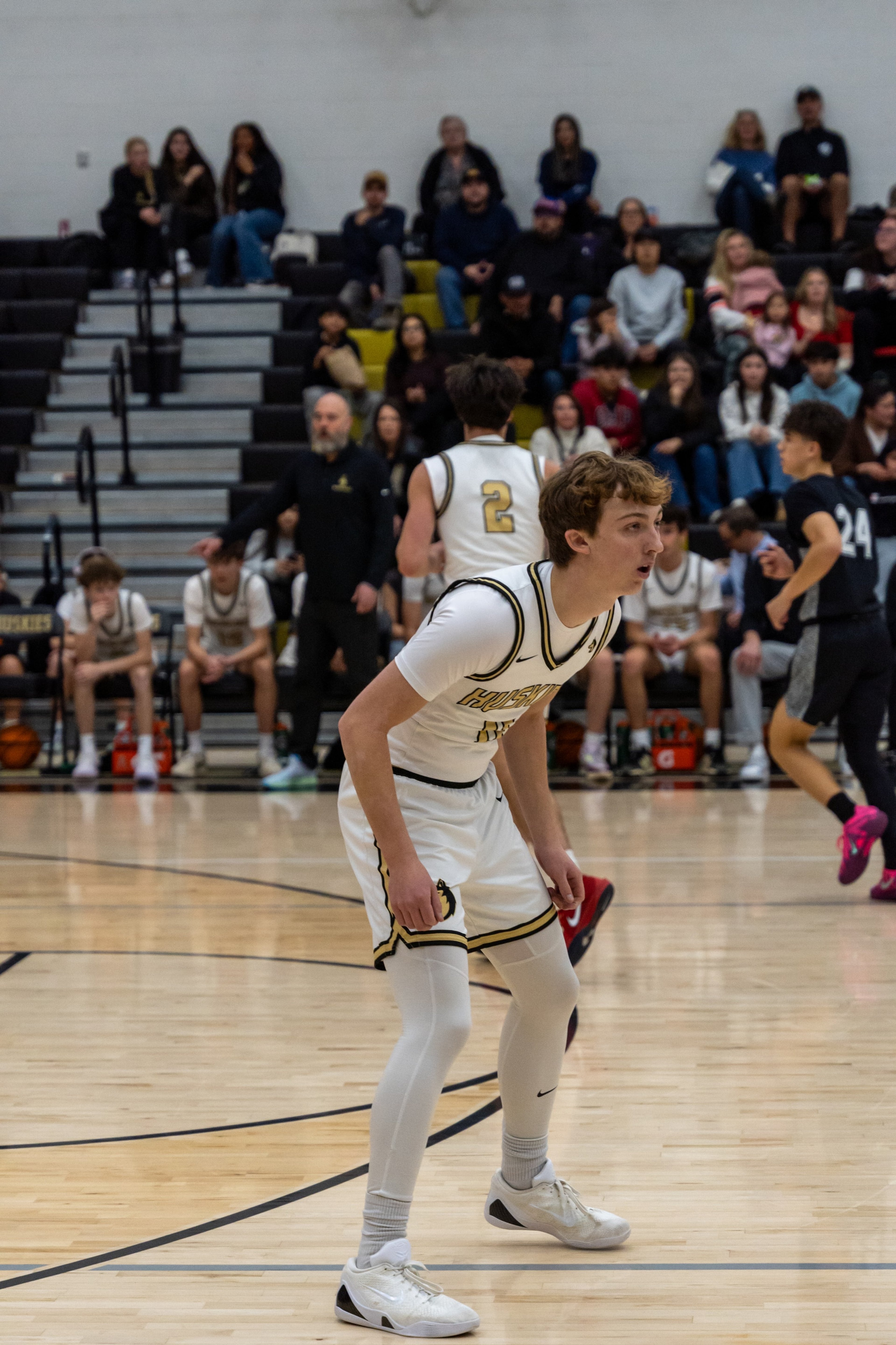 A basketball player leans forward and watches the play develop