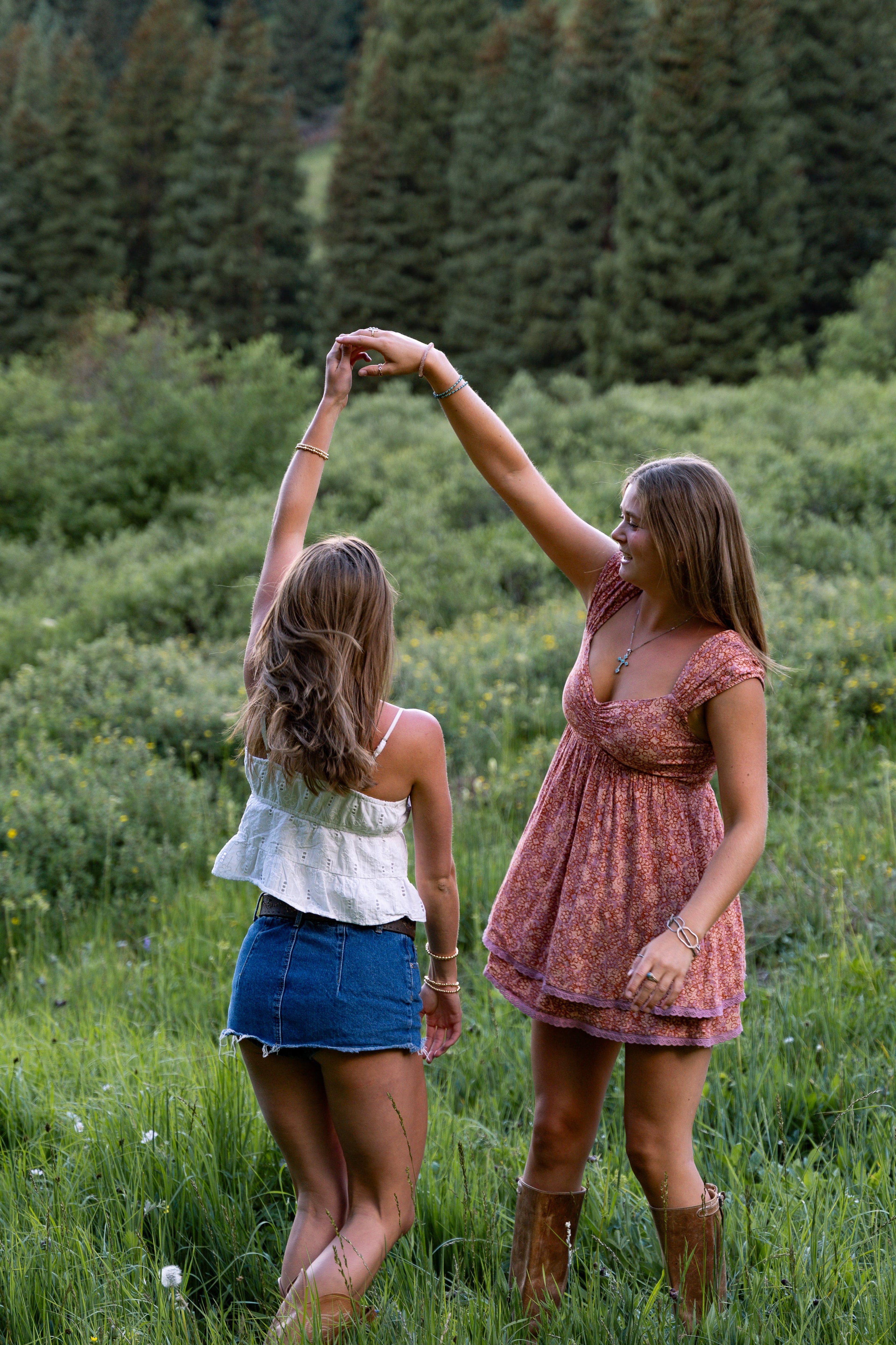 Two friends mid-dance in the meadow, skirts swinging