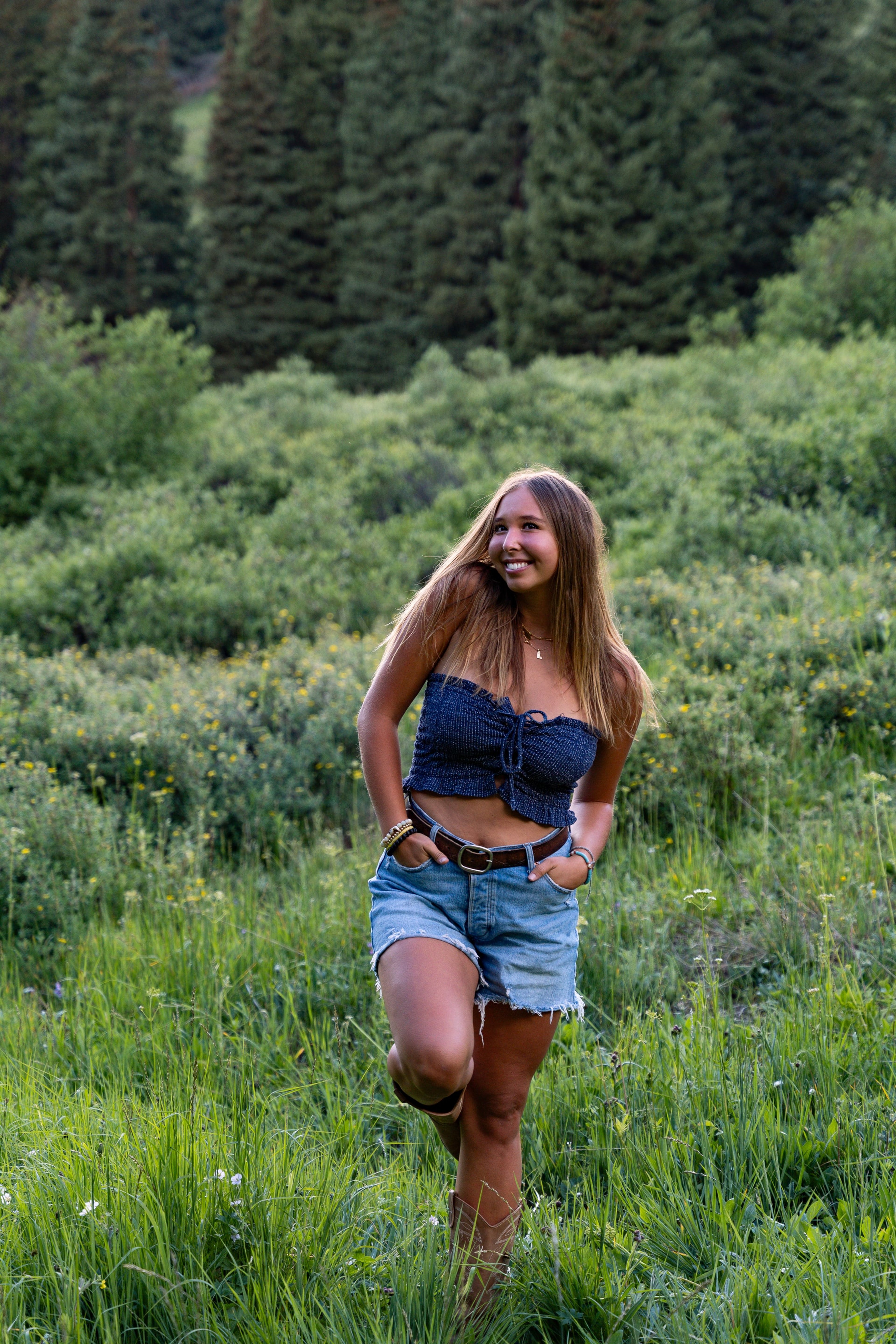A girl in denim standing hands-on-hips in the green meadow