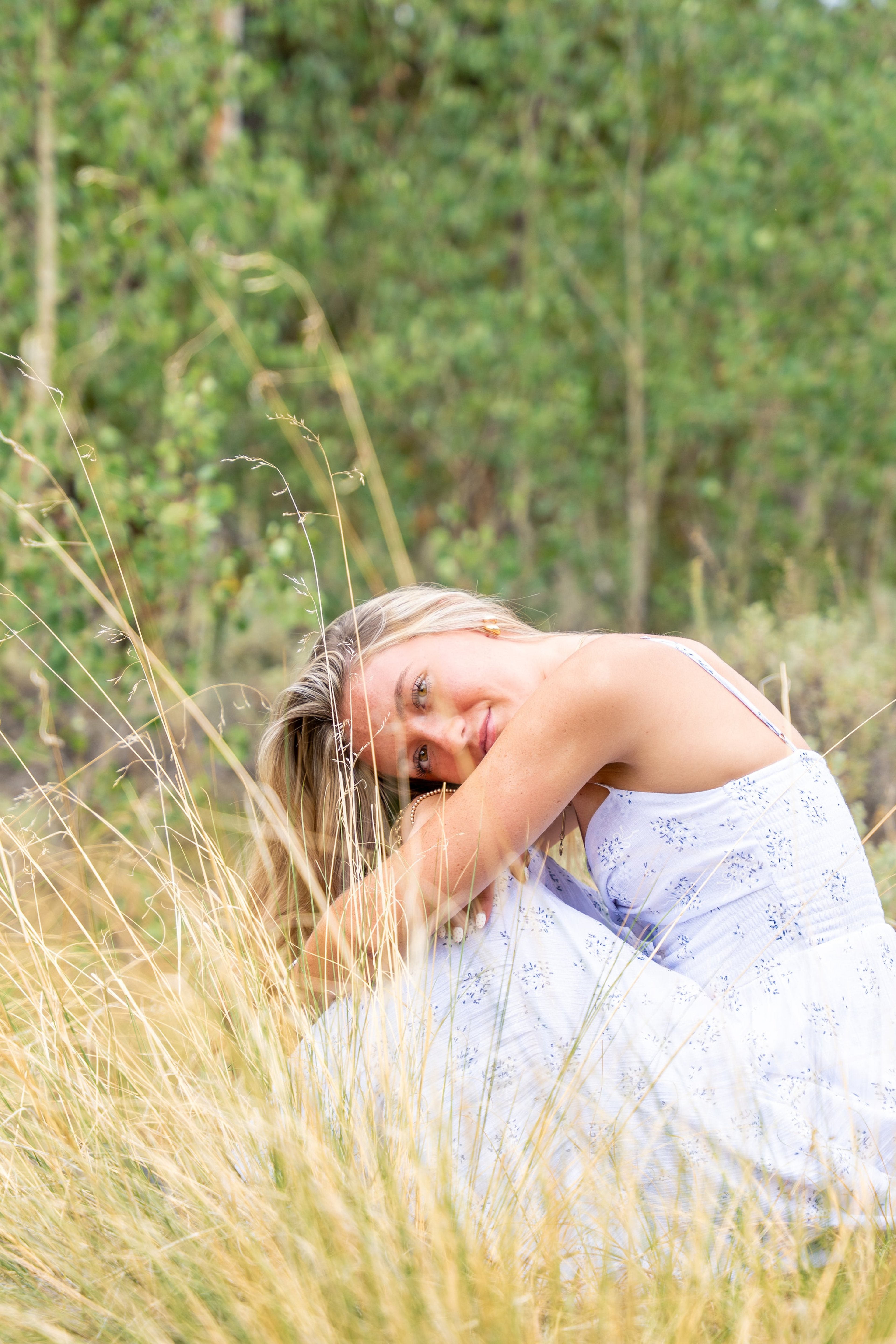 Caleigh resting her head on her knees in soft meadow grass