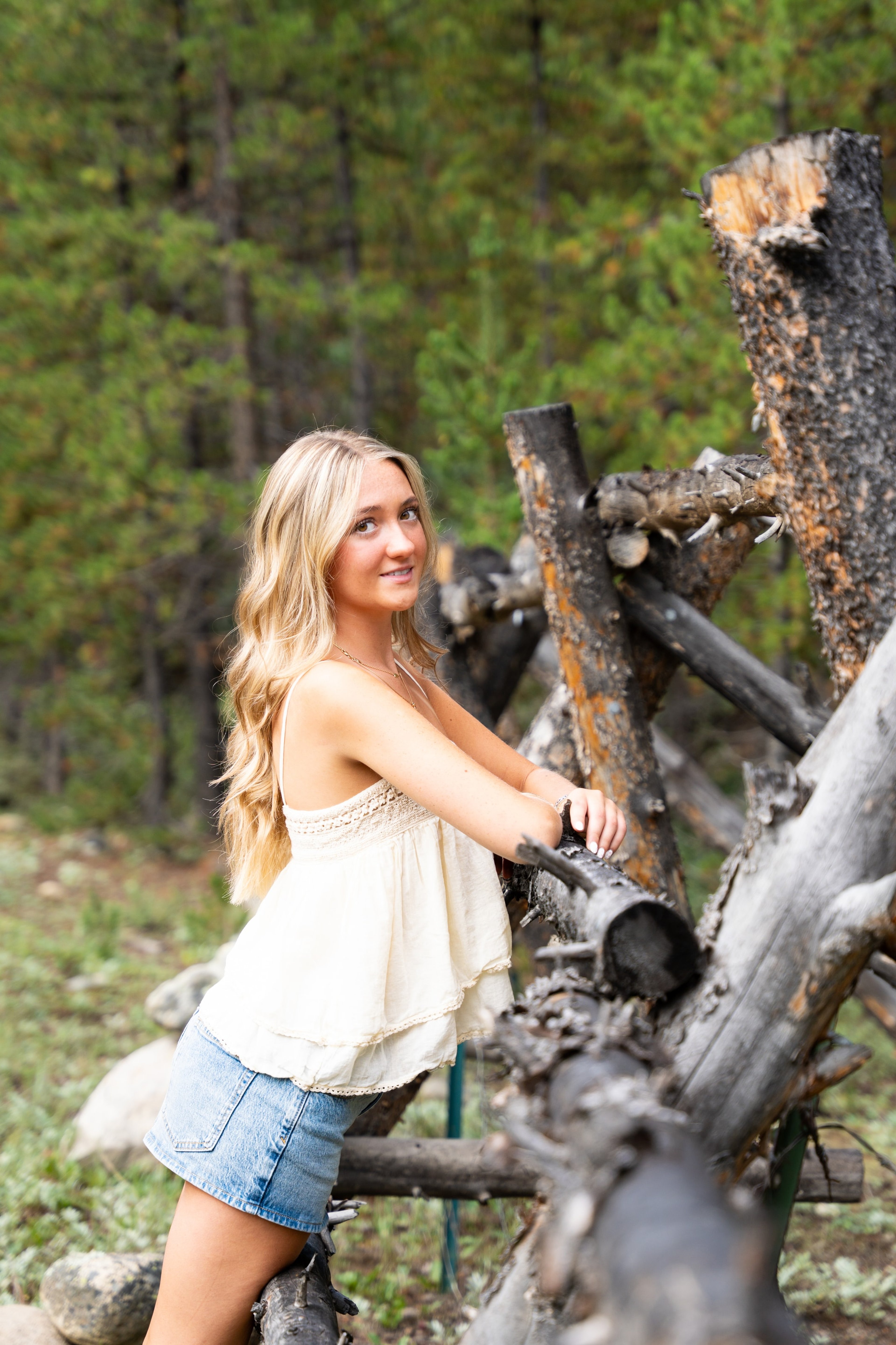 Caleigh leaning on a split-rail fence in the woods