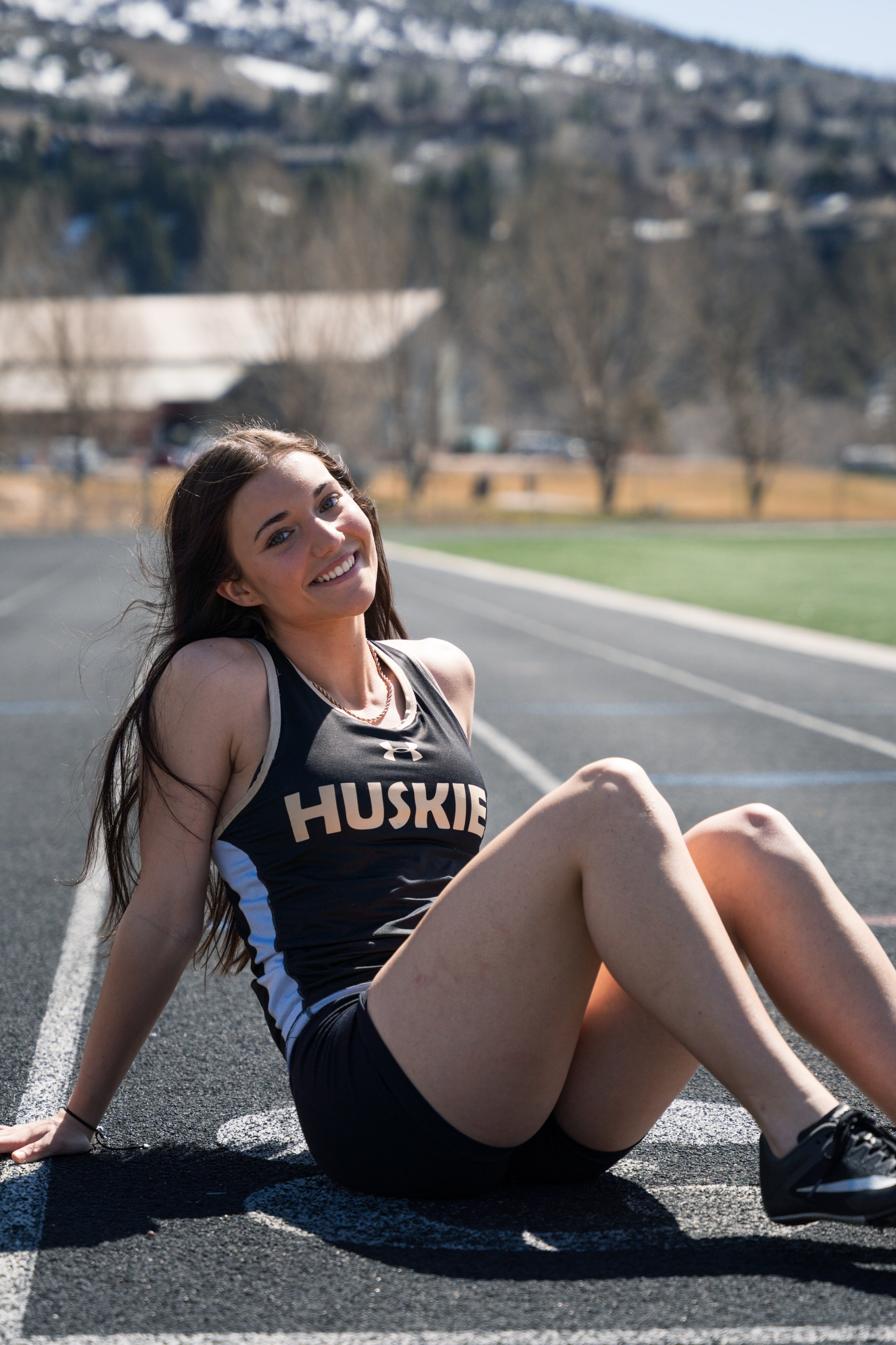 Lucy laughing seated on the track in afternoon sun