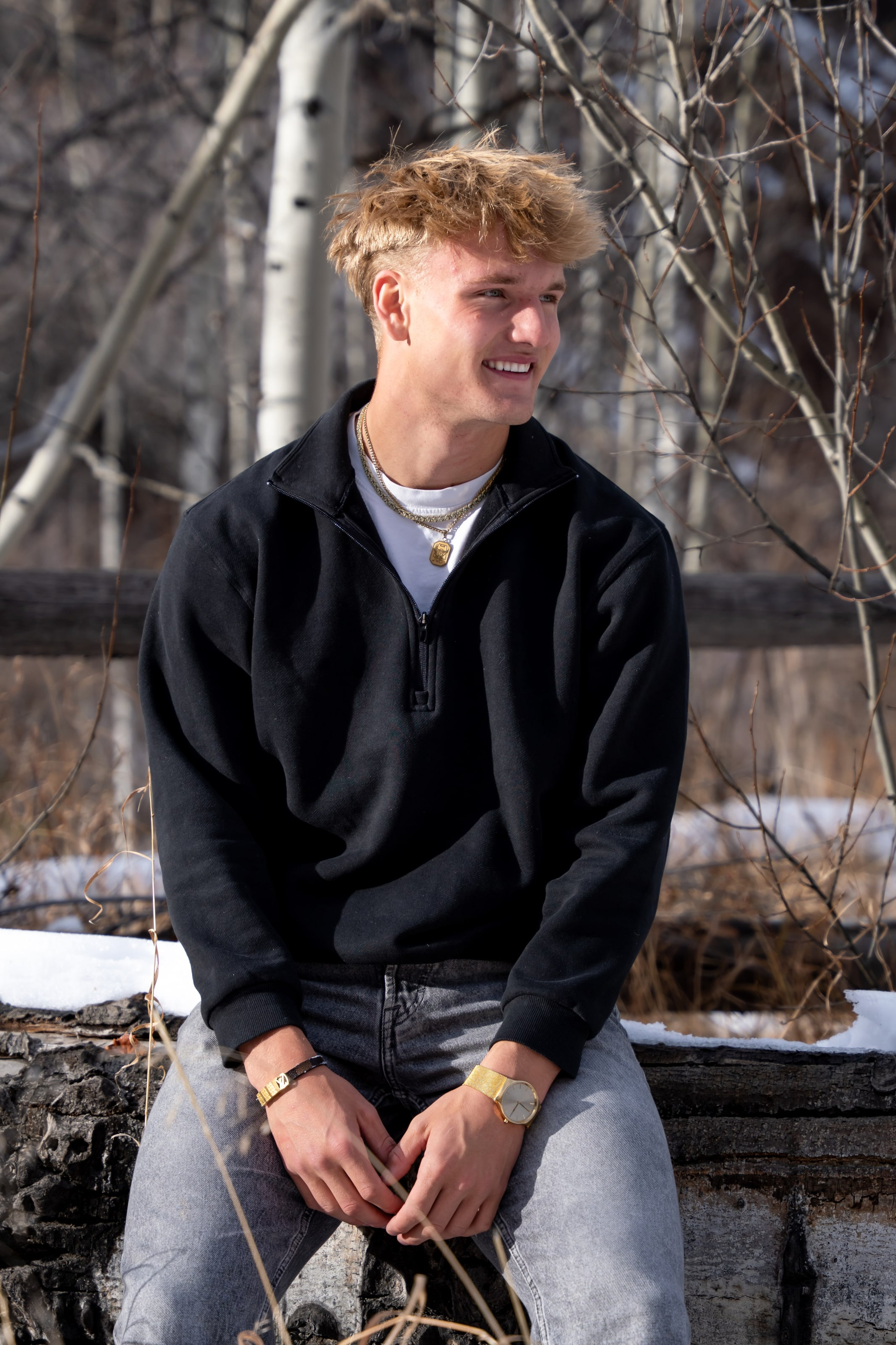 Jakob in a black quarter-zip seated at the fence line