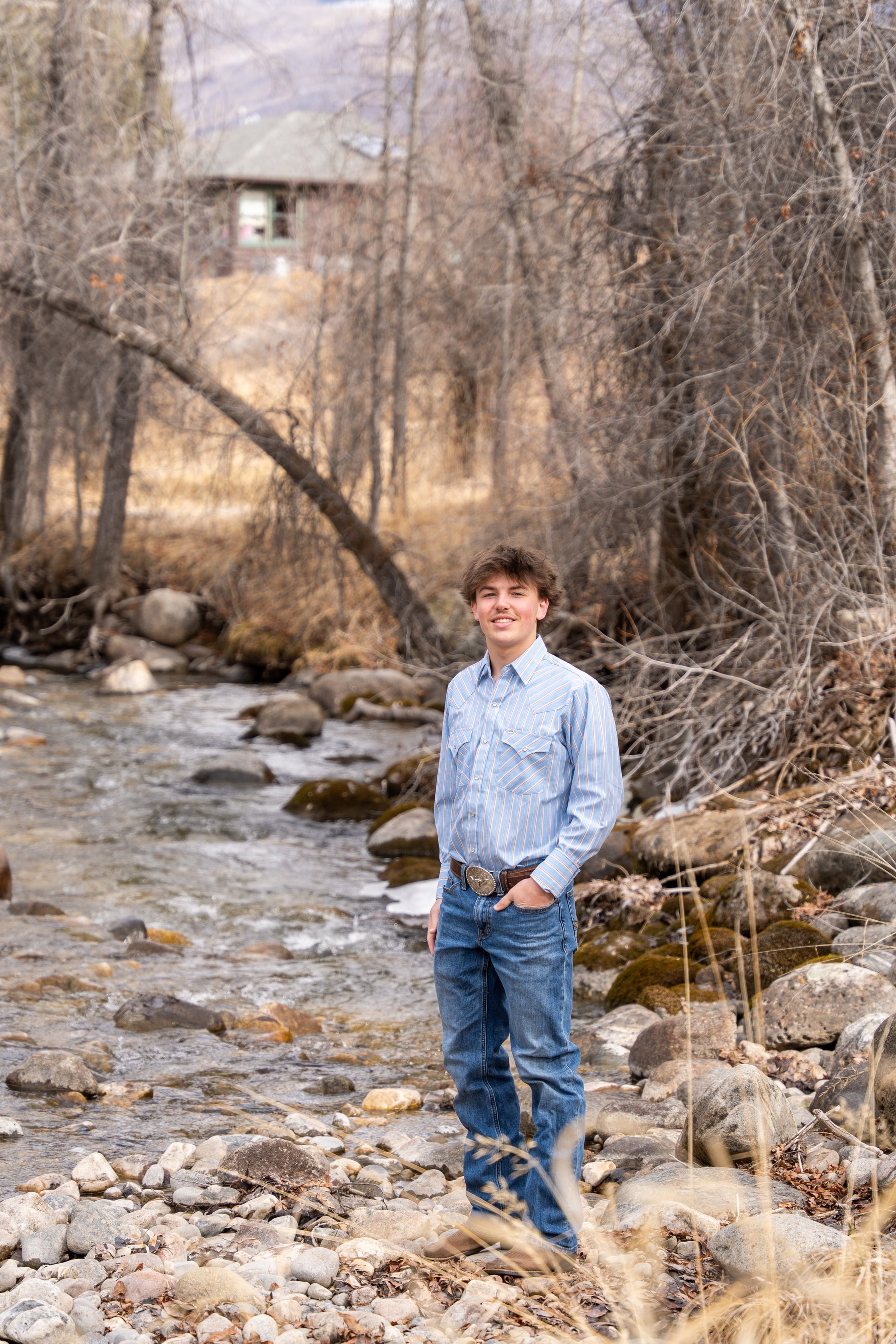 Teagan standing at a rocky creek under bare cottonwoods