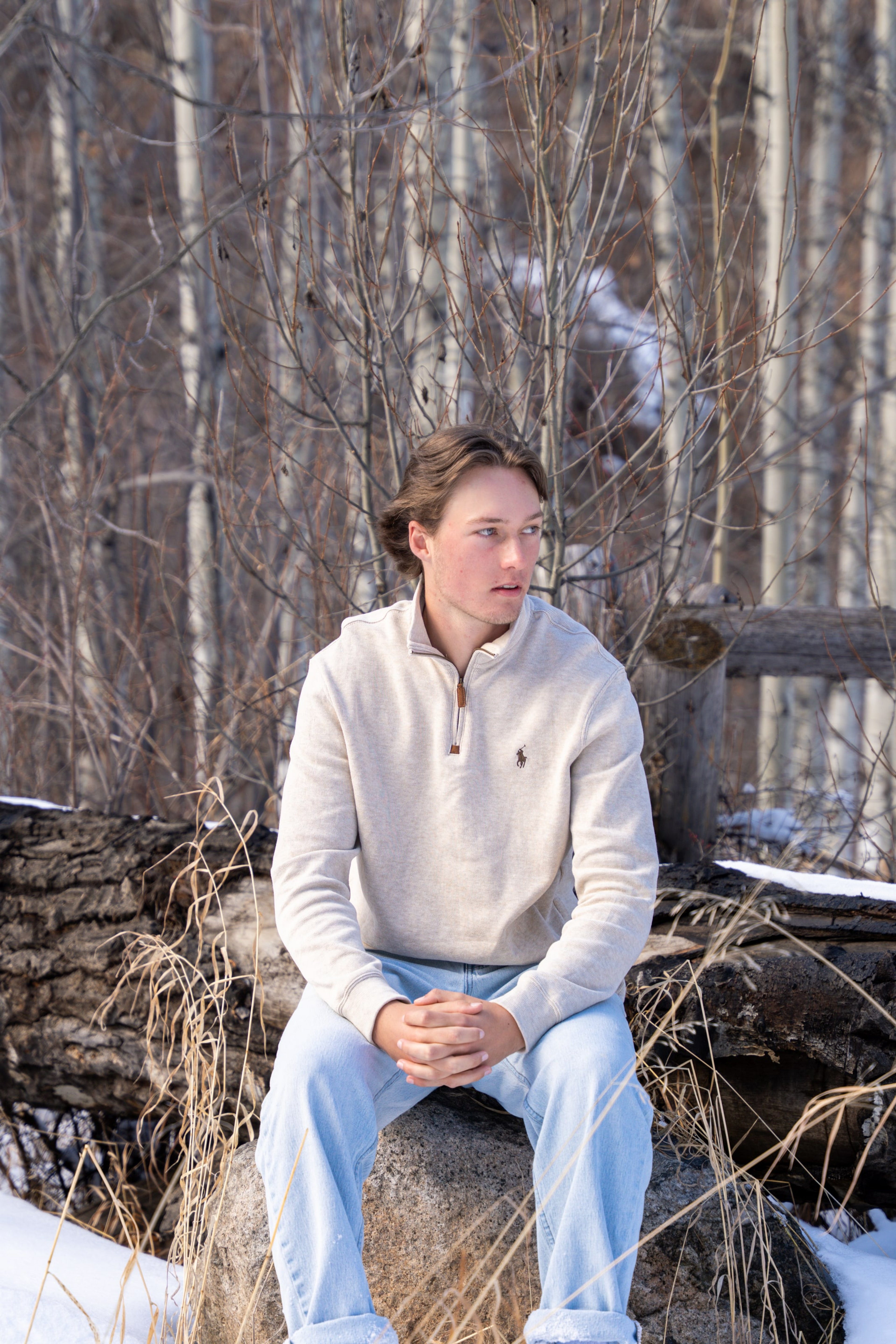 Caeden sitting on the aspen-grove wall, hands folded