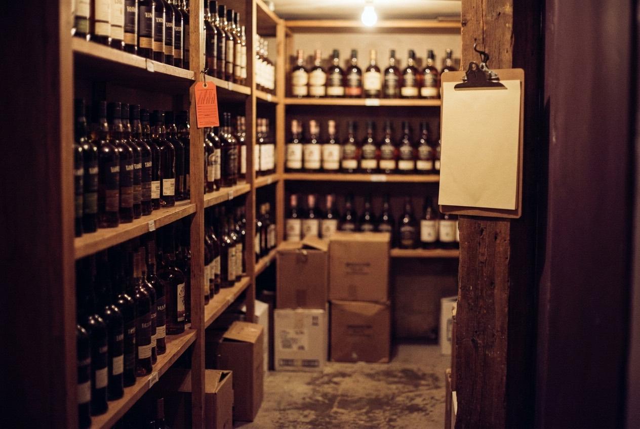 A tidy stock room after a delivery: cases on the shelves, a clipboard on its hook.
