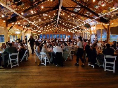 Event hosted at Laurelwood Retreat Center decorated with lights, people sitting at tables being served food and drinks by staff