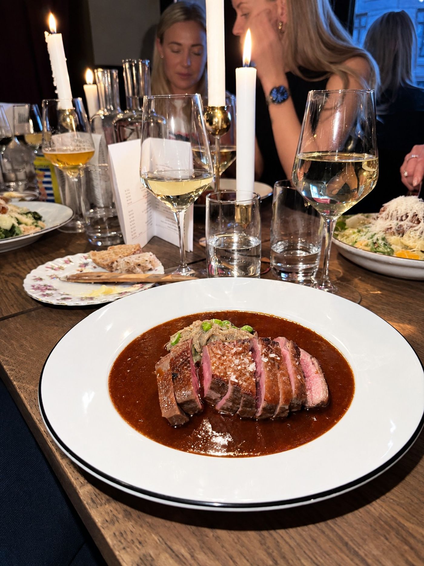 Skivat kött i mörk sås på vit tallrik vid ett dukat bord, Bistro Breve