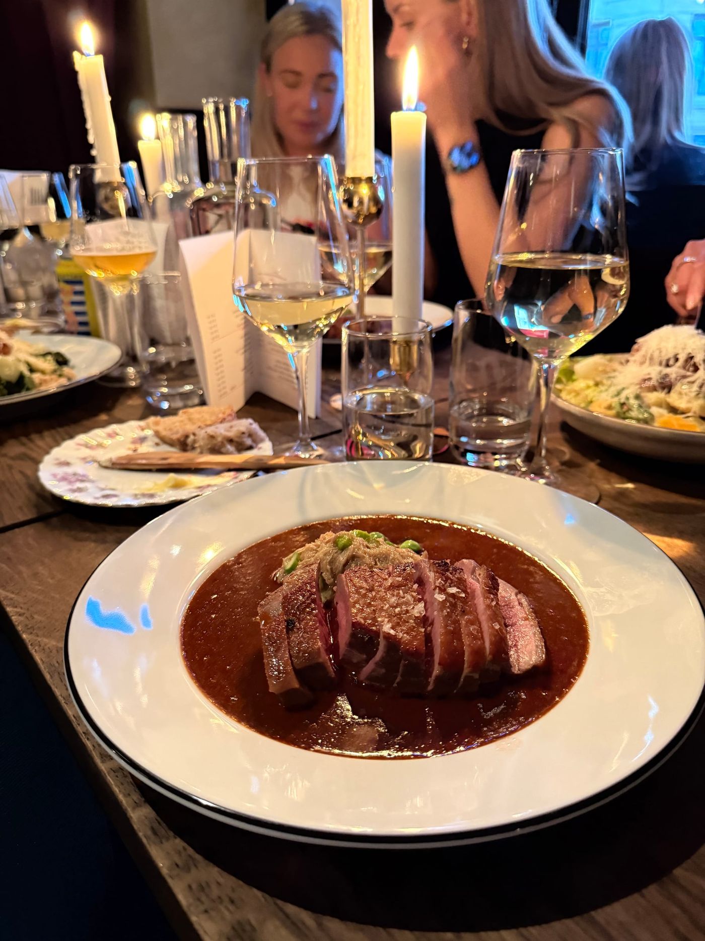 Skivat kött i mörk sås på vit tallrik vid ett dukat bord, Bistro Breve