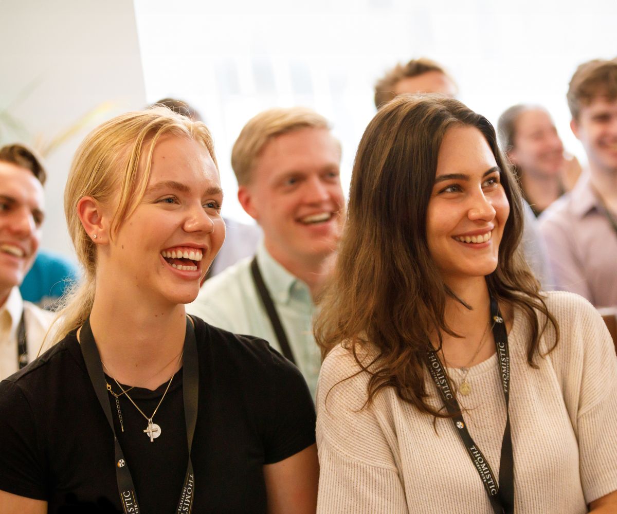 two students smiling while listening to a lecture