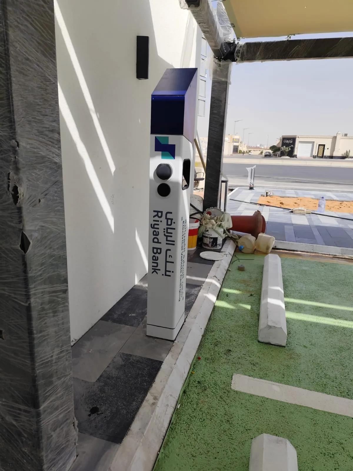 لقطة قريبة لشاحن Etrel بهوية بنك الرياض بجانب موقف مطلي