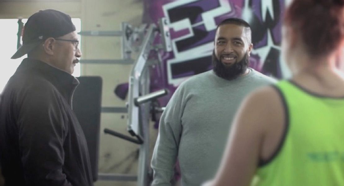 Three men smiling at each other in a gym