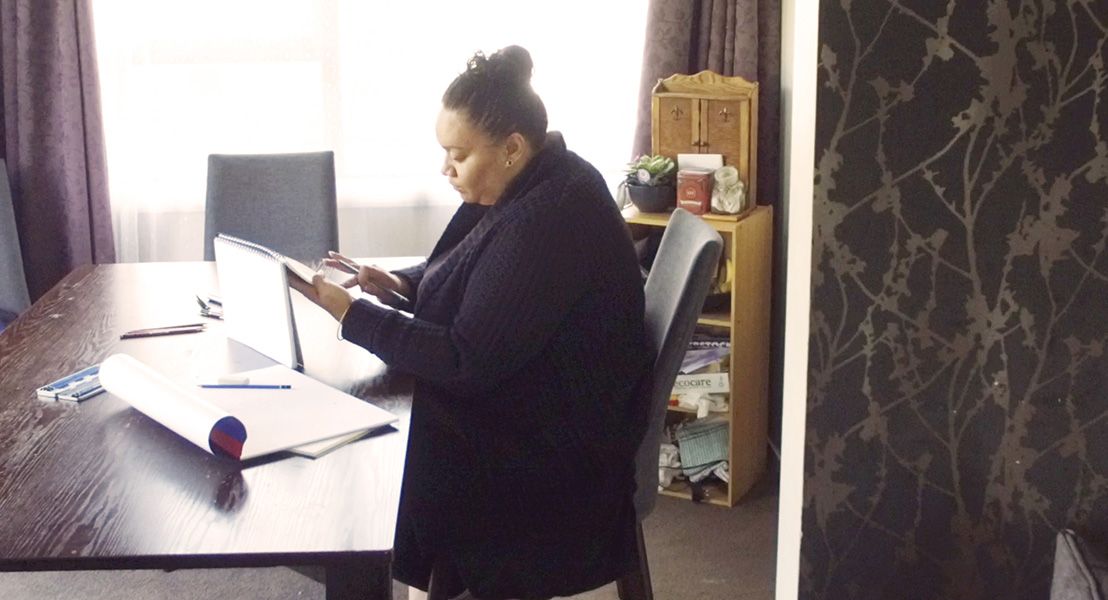 woman sitting at kitchen table holding a notebook