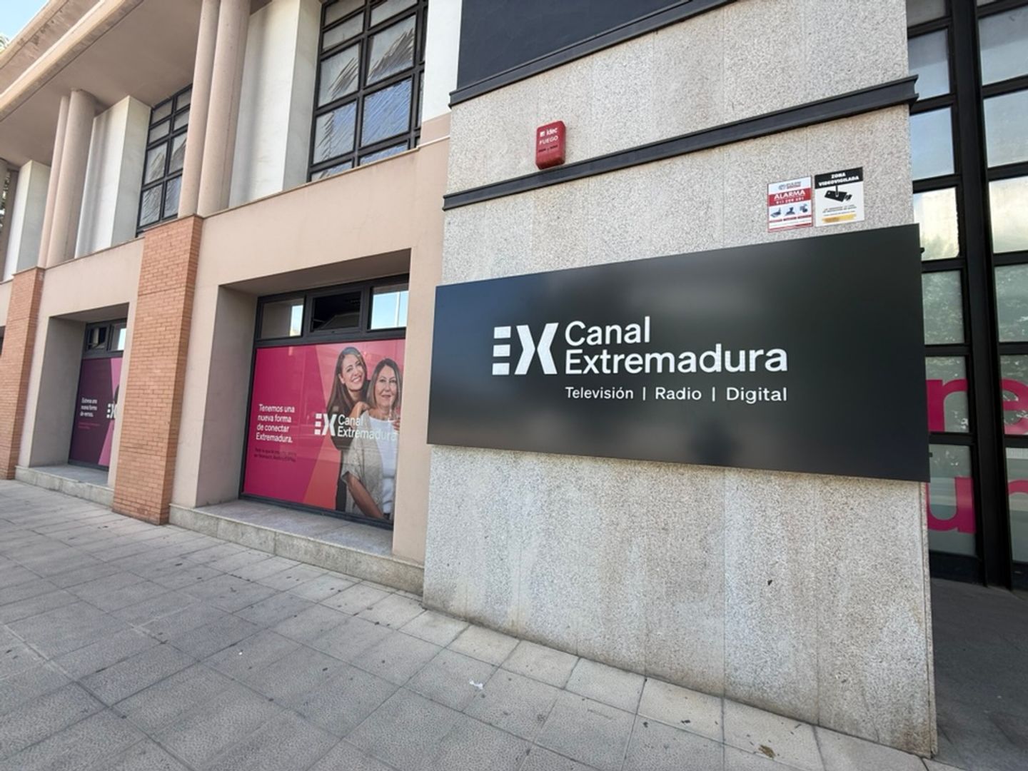 Fachada de la sede de Canal Extremadura con el rótulo corporativo nuevo y los vinilos de la campaña en los ventanales